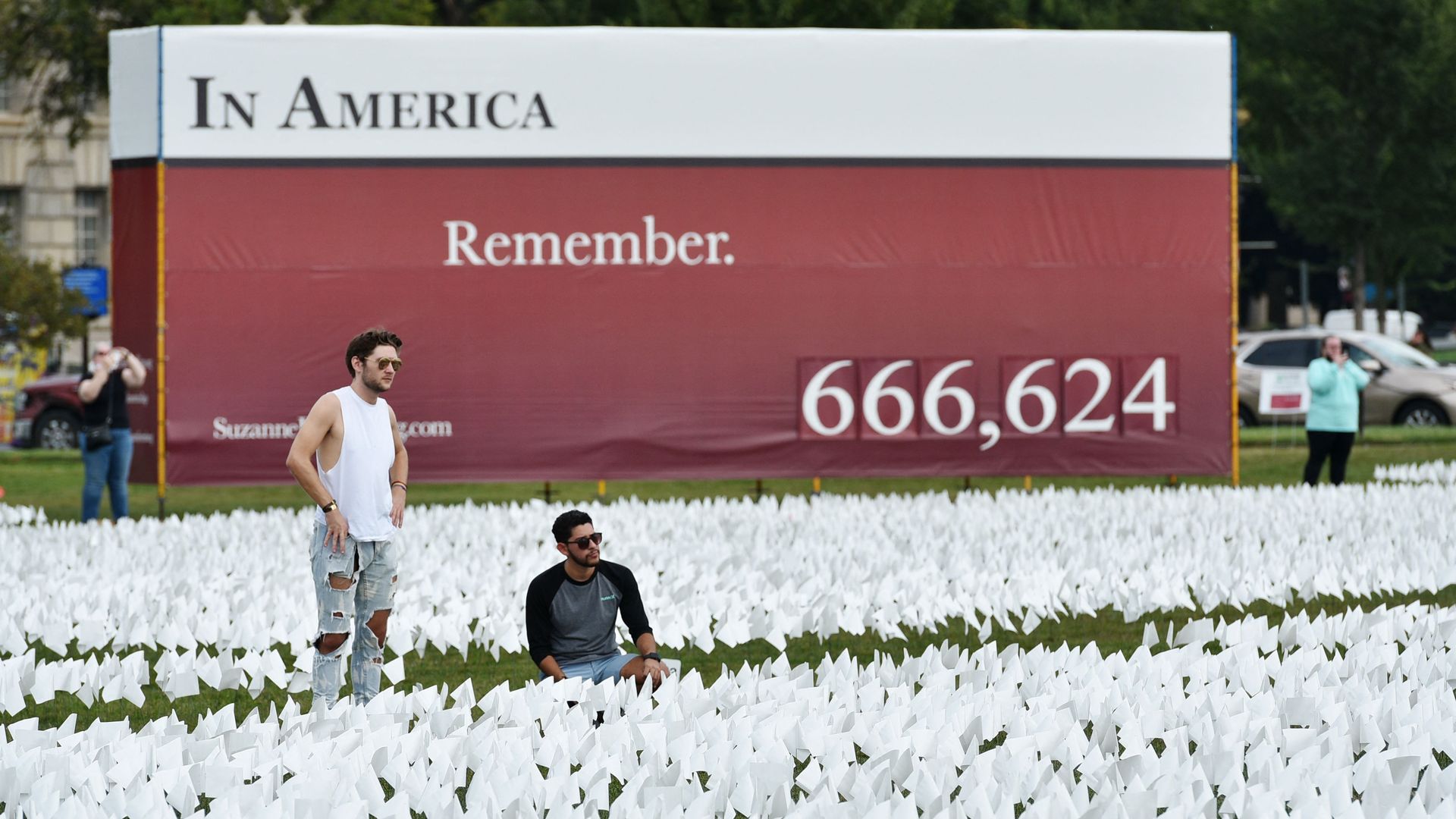 Two men are seen looking at flags on the National Mall recalling the more than 666,000 Americans killed by COVID-19.