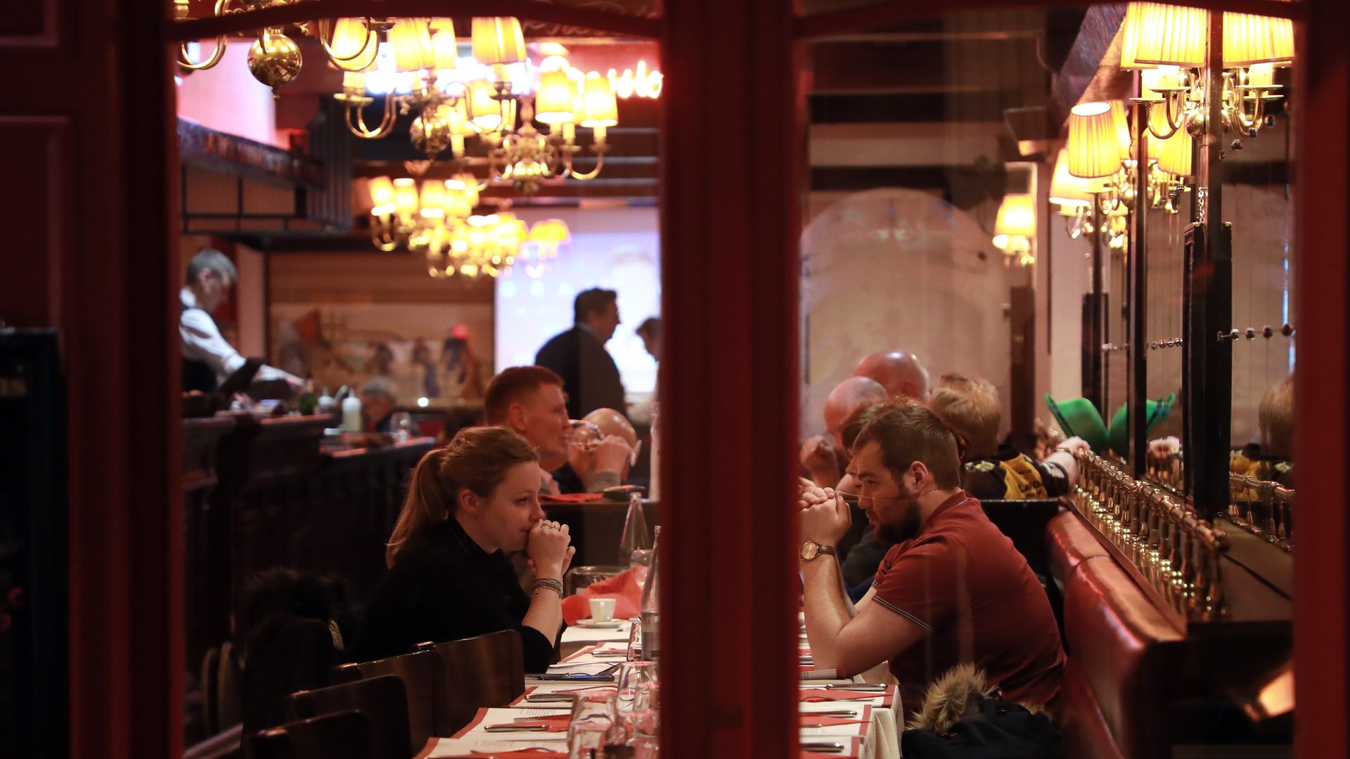 In this image, two people sit at a table in a restaurant