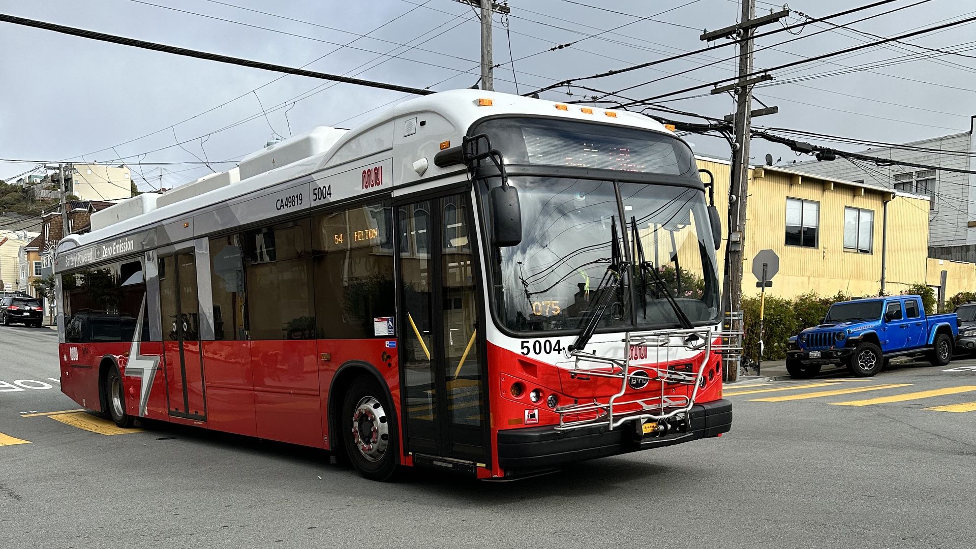 A red zero-emission bus driving through an intersection.
