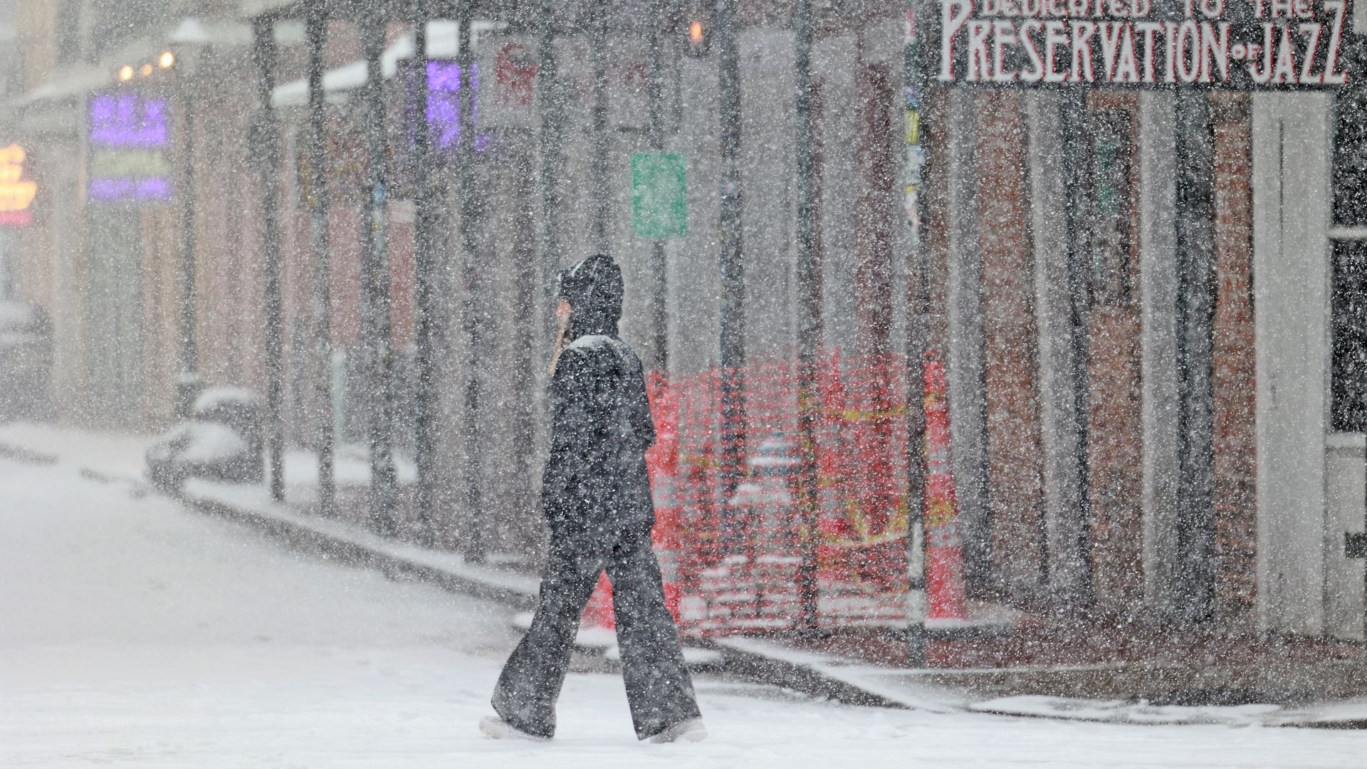 A woman walking down Bourbon Street in the snow. 