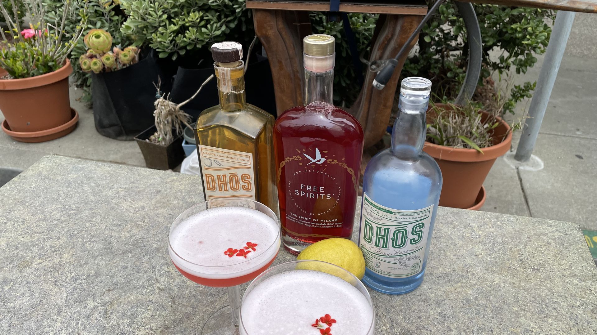 two cocktails sitting in front of three bottles on a table