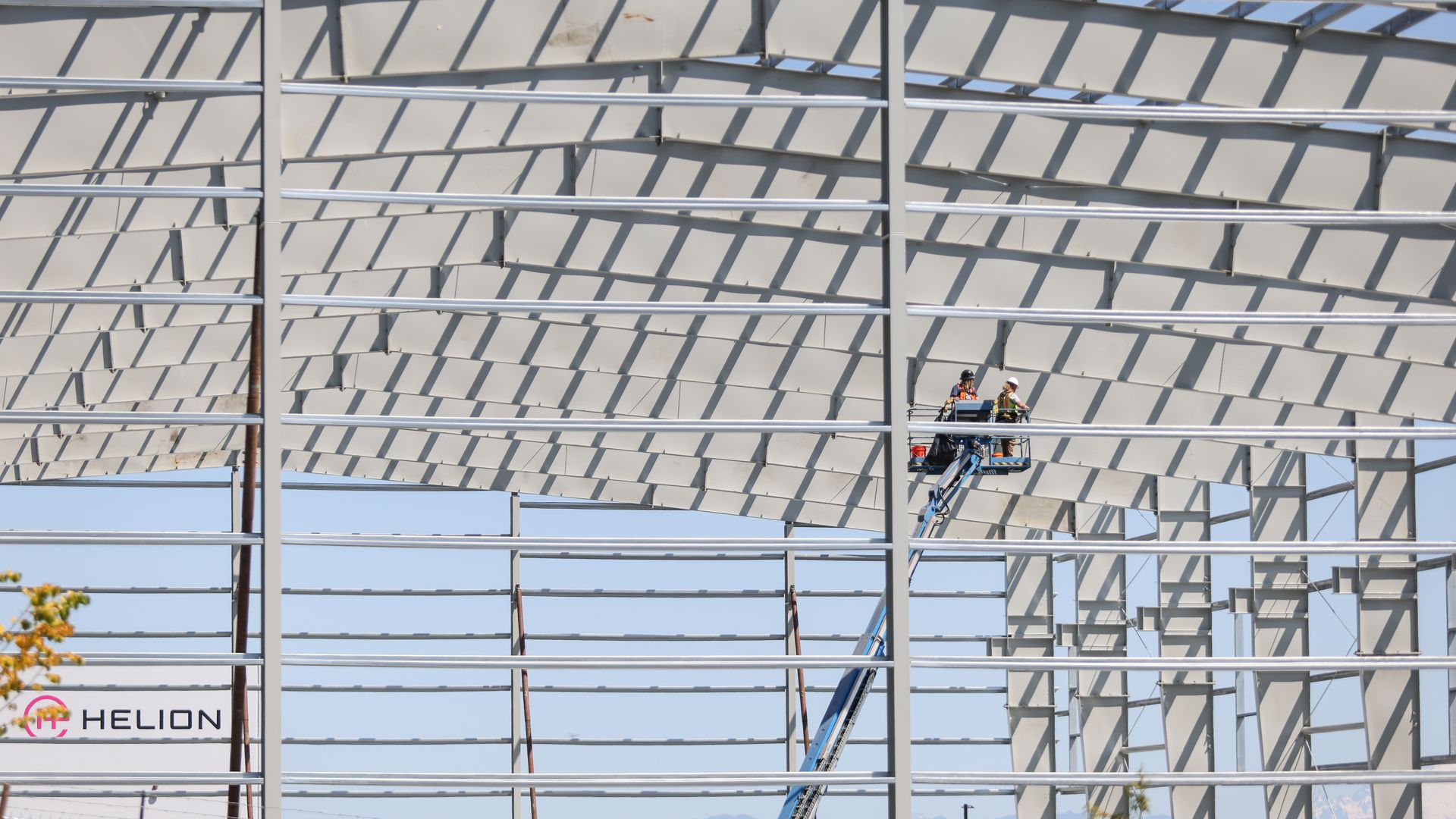 Workers on a lift install the steel frame of a Helion Energy fusion power plant building under construction.