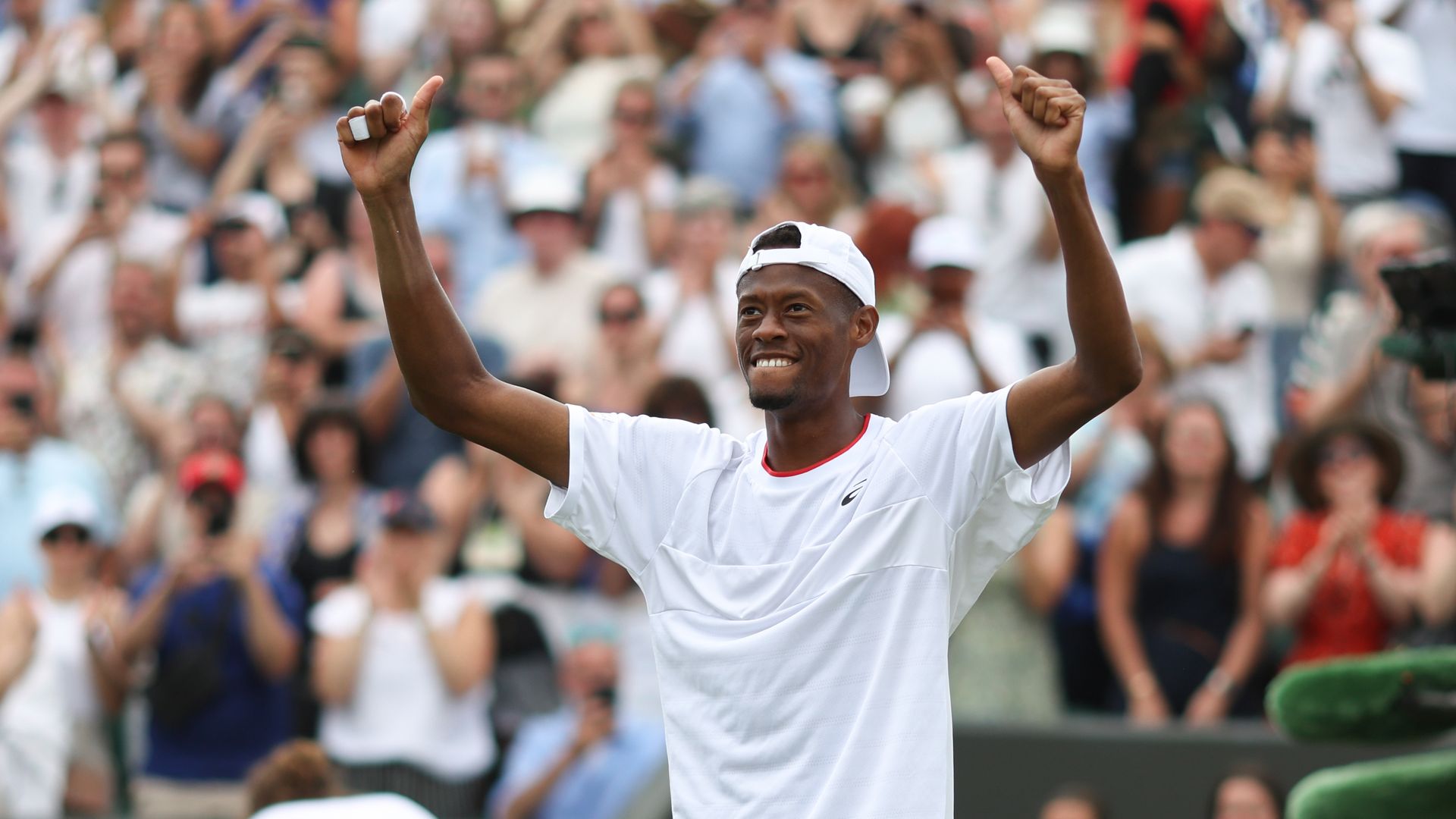 A tennis player wearing all white raises his hands in victory after winning a match against a top-ranked player