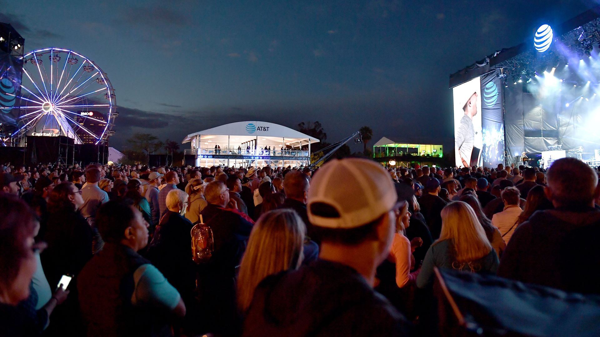 A festival with a stage and ferris wheel. 