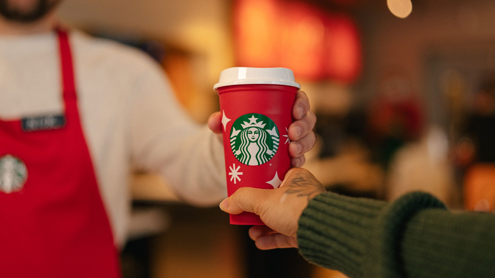 Starbucks barista hands red cup to customer