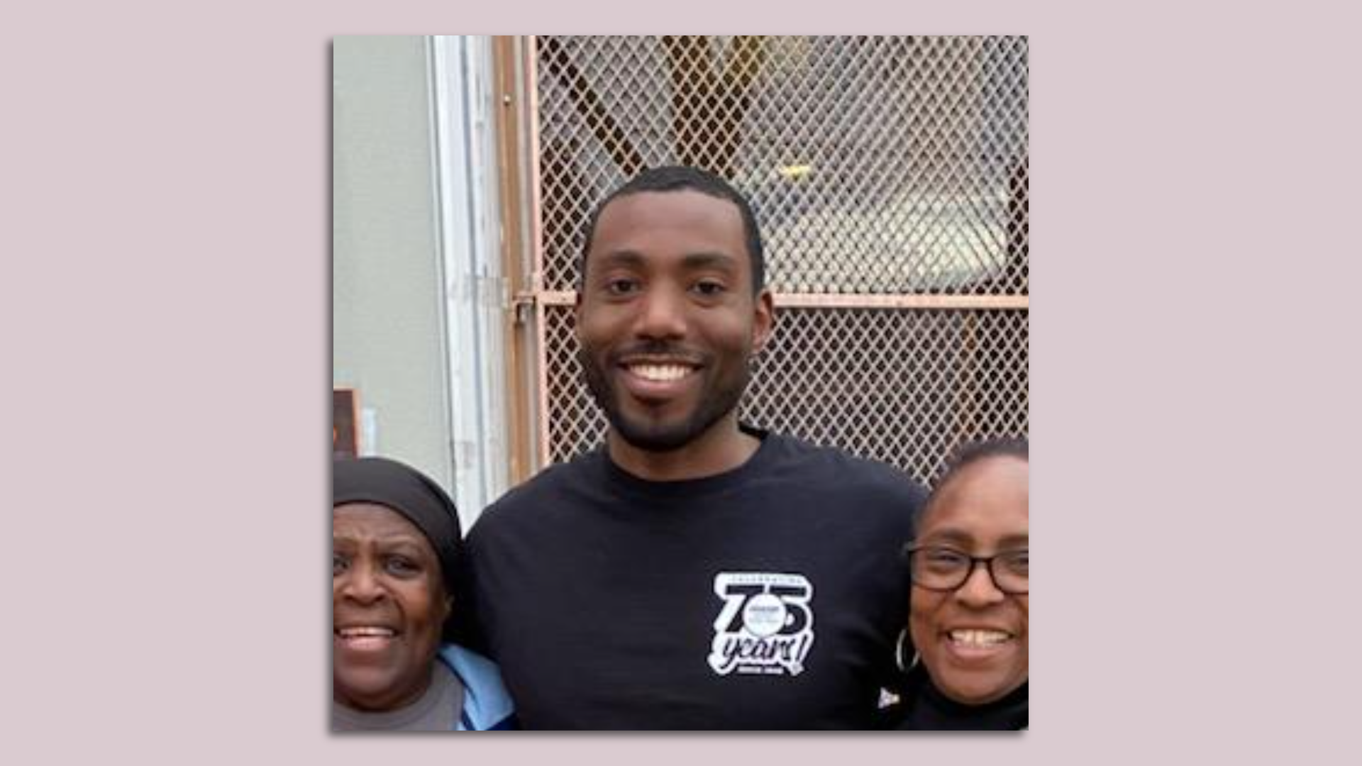 Donta Rose smiles while standing next to two women.