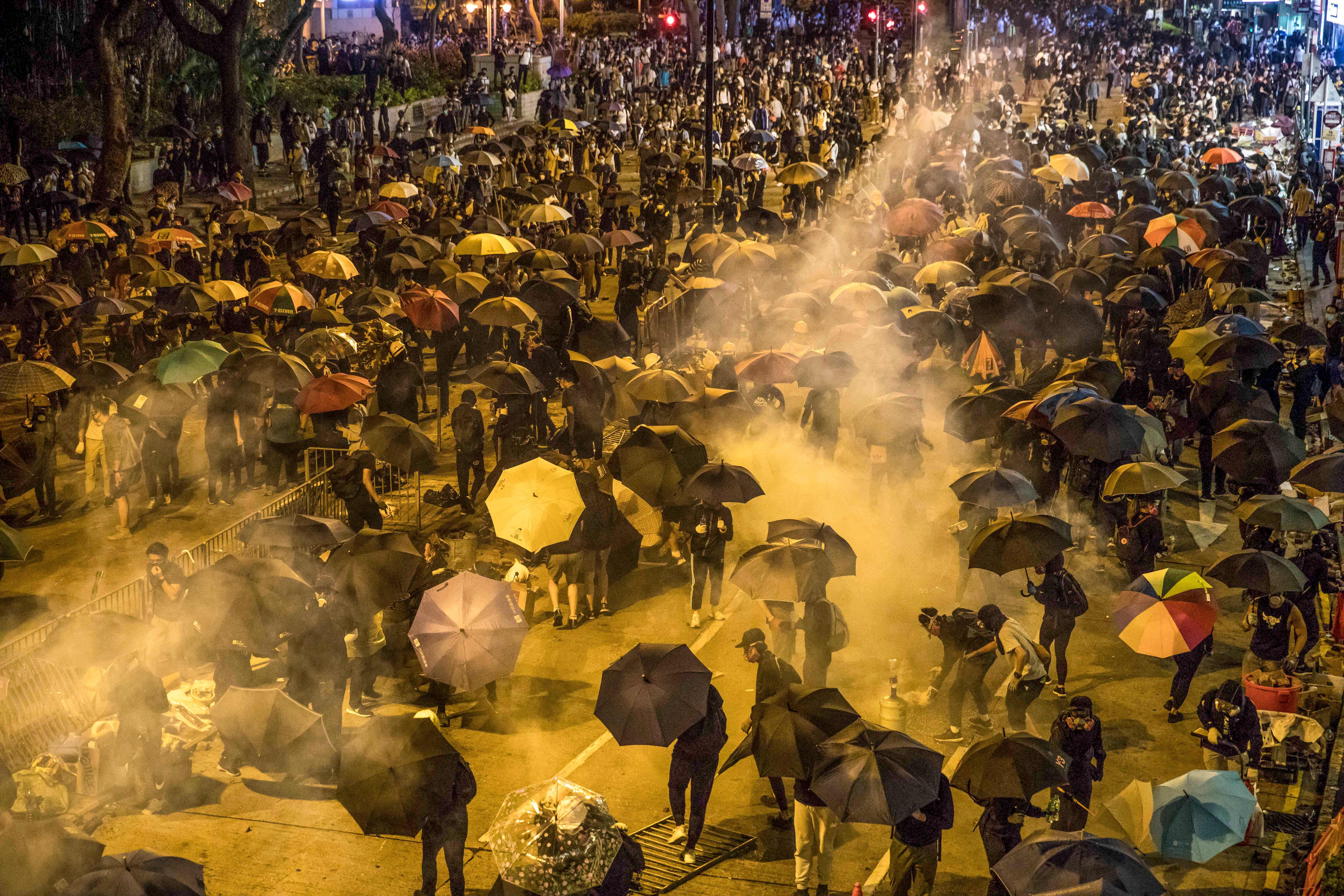 Protesters react as police fire tear gas while they attempt to march towards Hong Kong Polytechnic University in Hung Hom district of Hong Kong on November 18