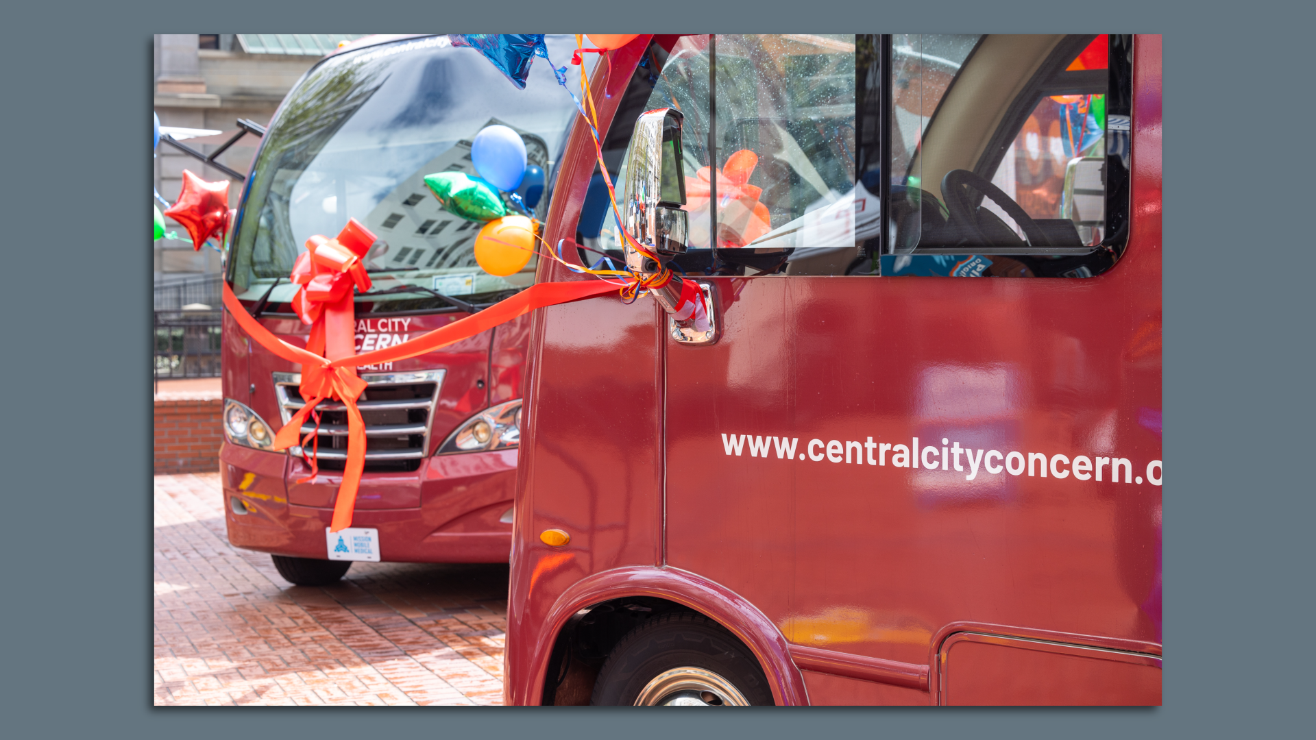Two red vans parked with ribbons on them, to be used as mobile clinics