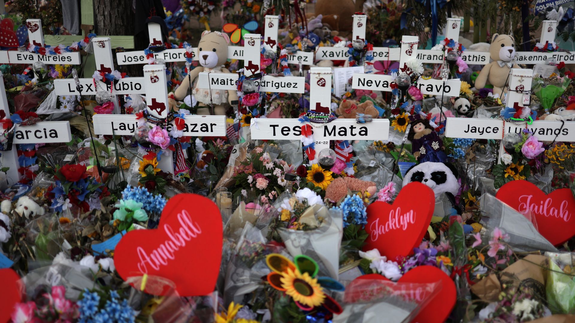 Photo of crosses bearing names of Uvalde shooting victims as they're surrounded by flowers and hearts