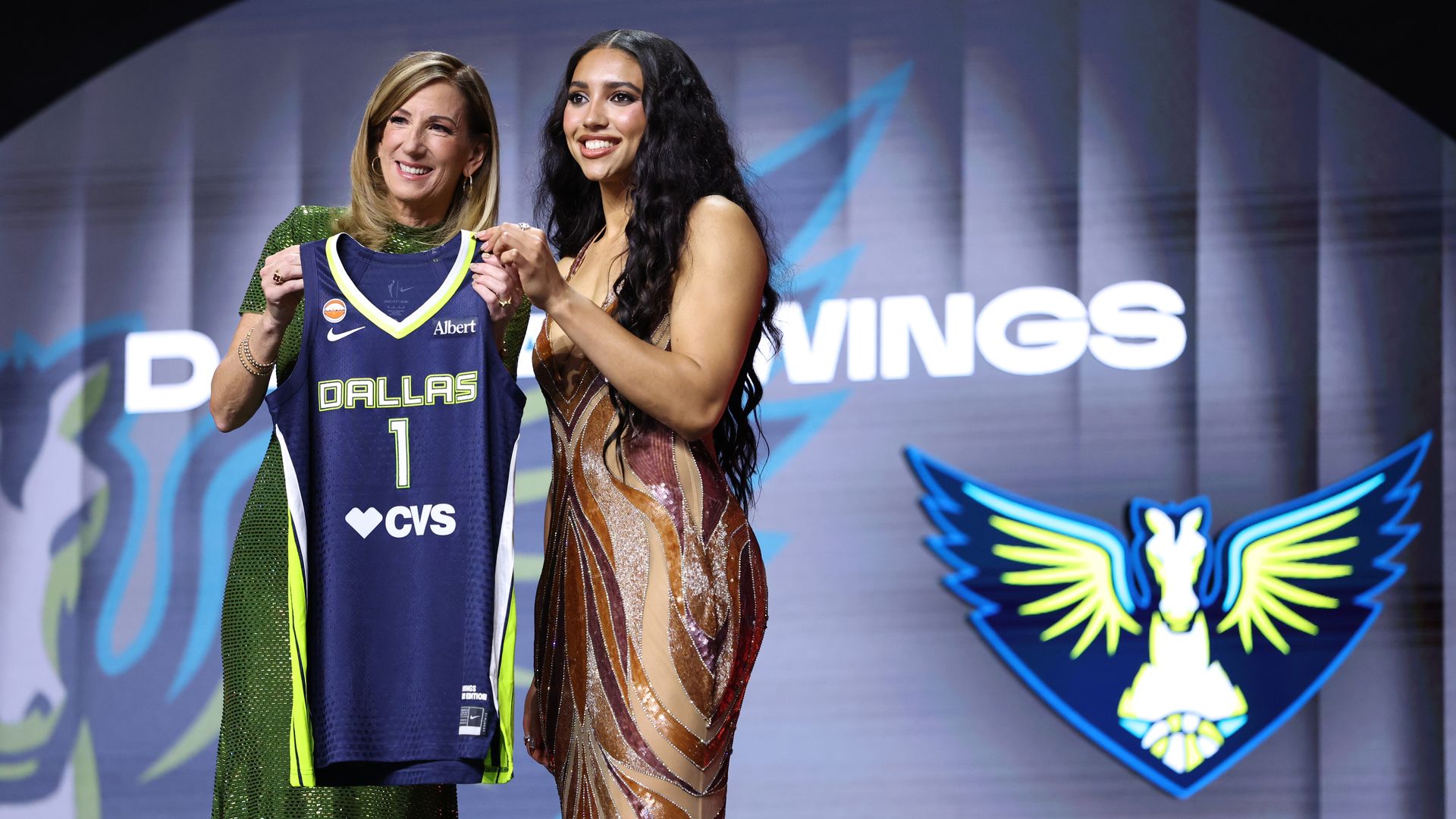 Cathy Engelbert and Azzi Fudd pose with a jersey on stage at the WNBA draft