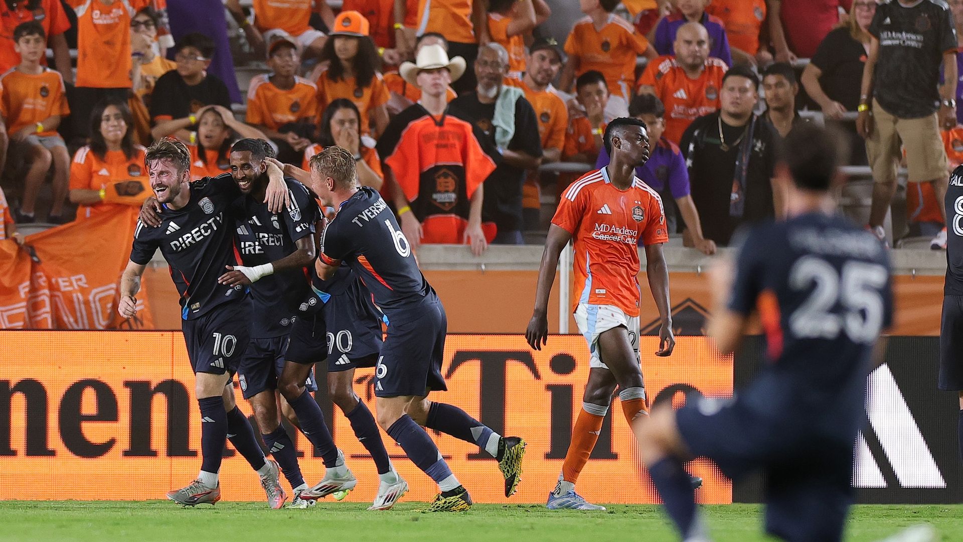 SDFC players hug and celebrate on the field after a goal.