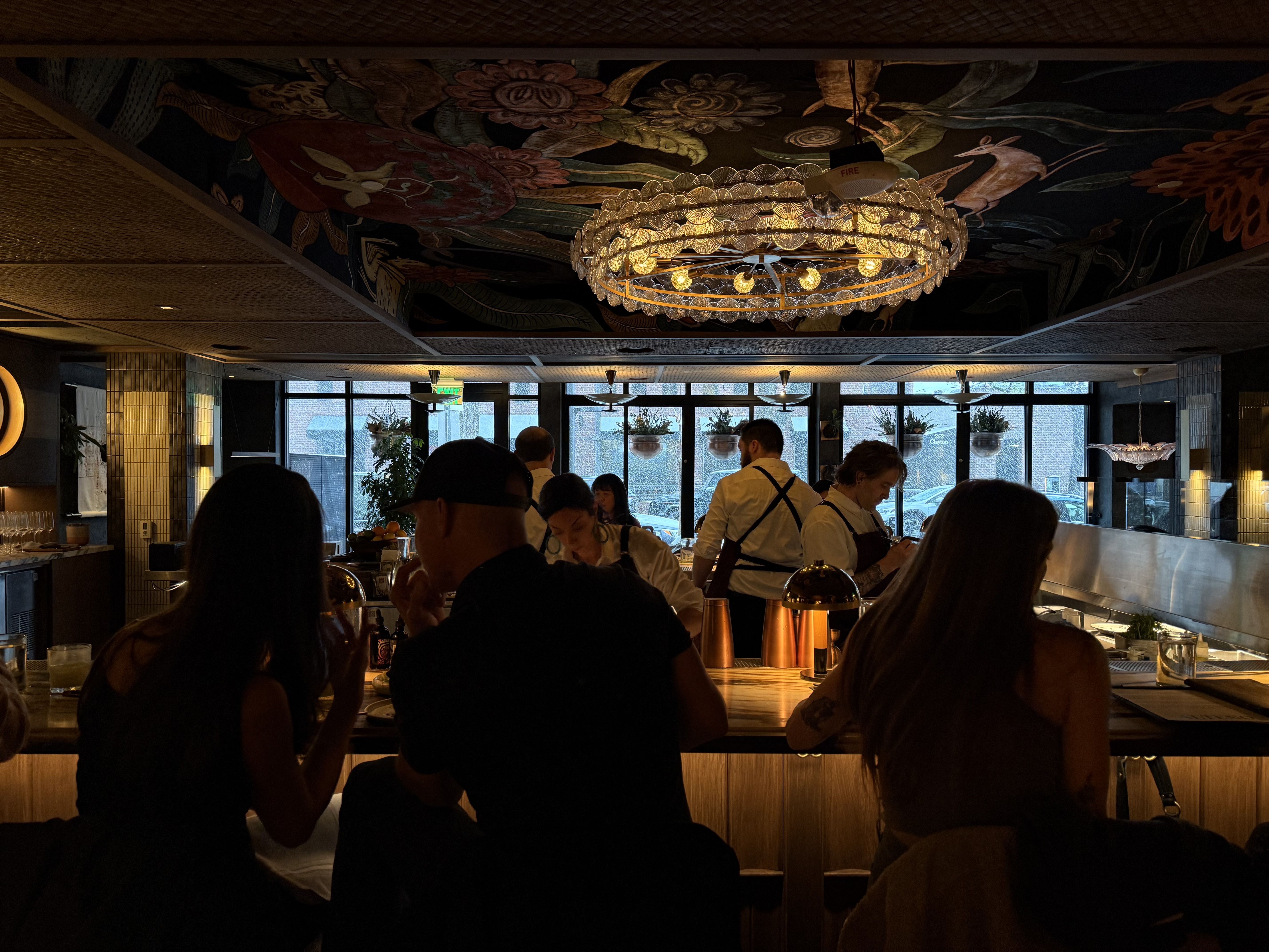 A bar with people and an overhead, circular light fixture. 