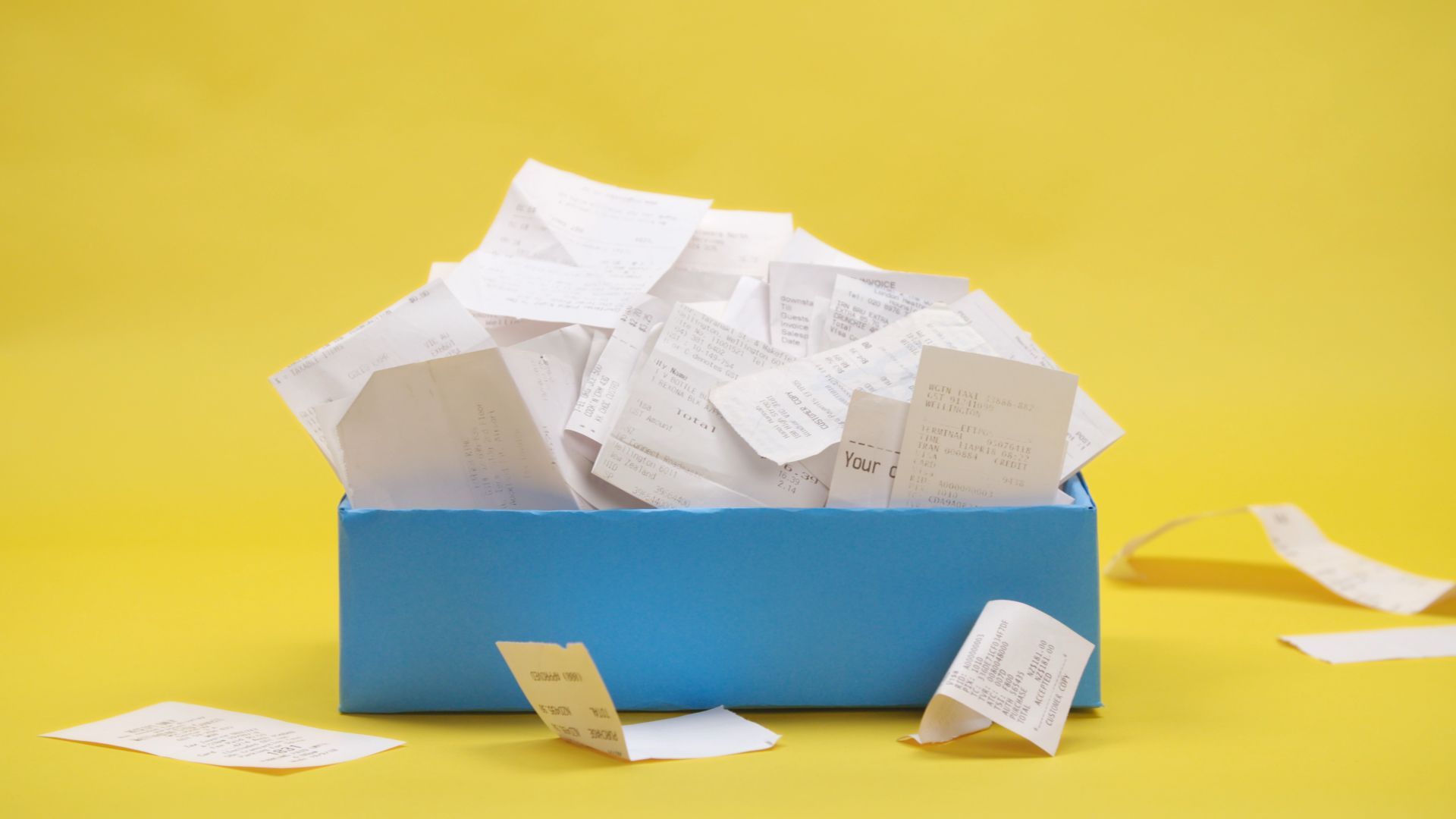 A blue box is filled with white receipts. 