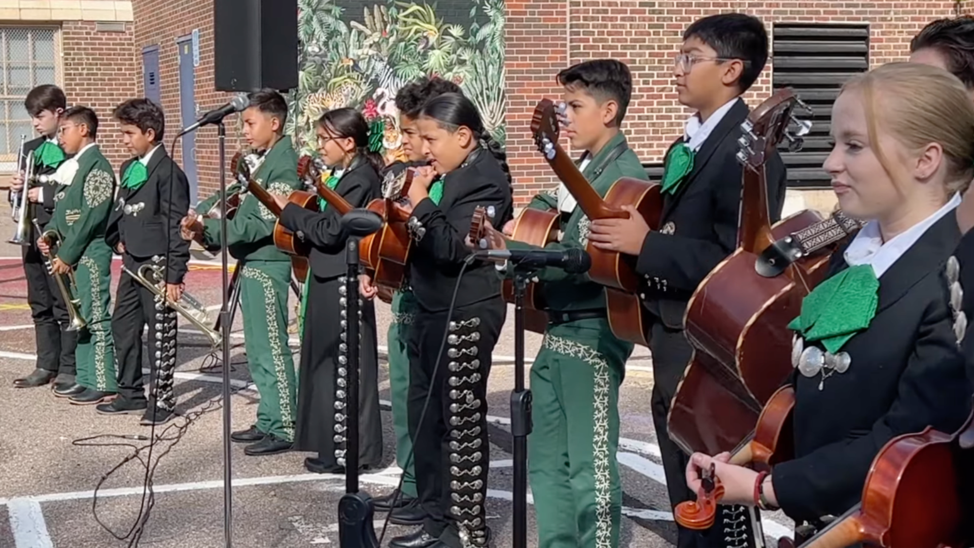 Several children in traditional mariachi outfits perform at a children's playground. 