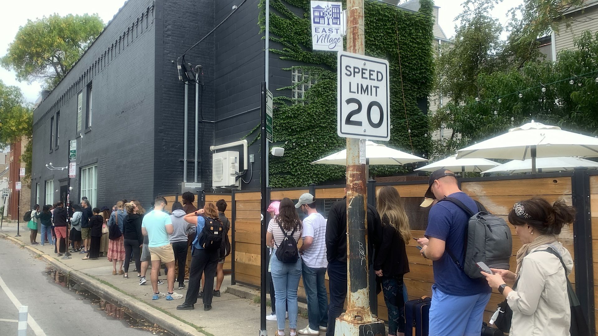 Line of people in front of a black building.