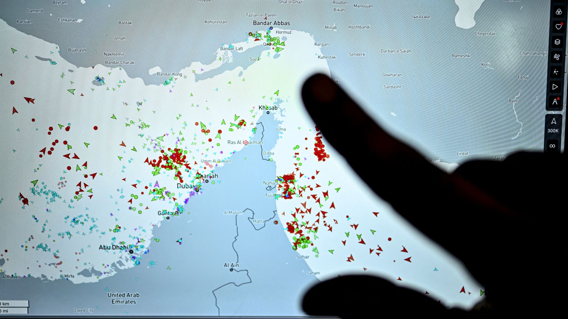A person points at a computer screen showing vessel traffic near Iran on the MarineTraffic ship-tracking website.