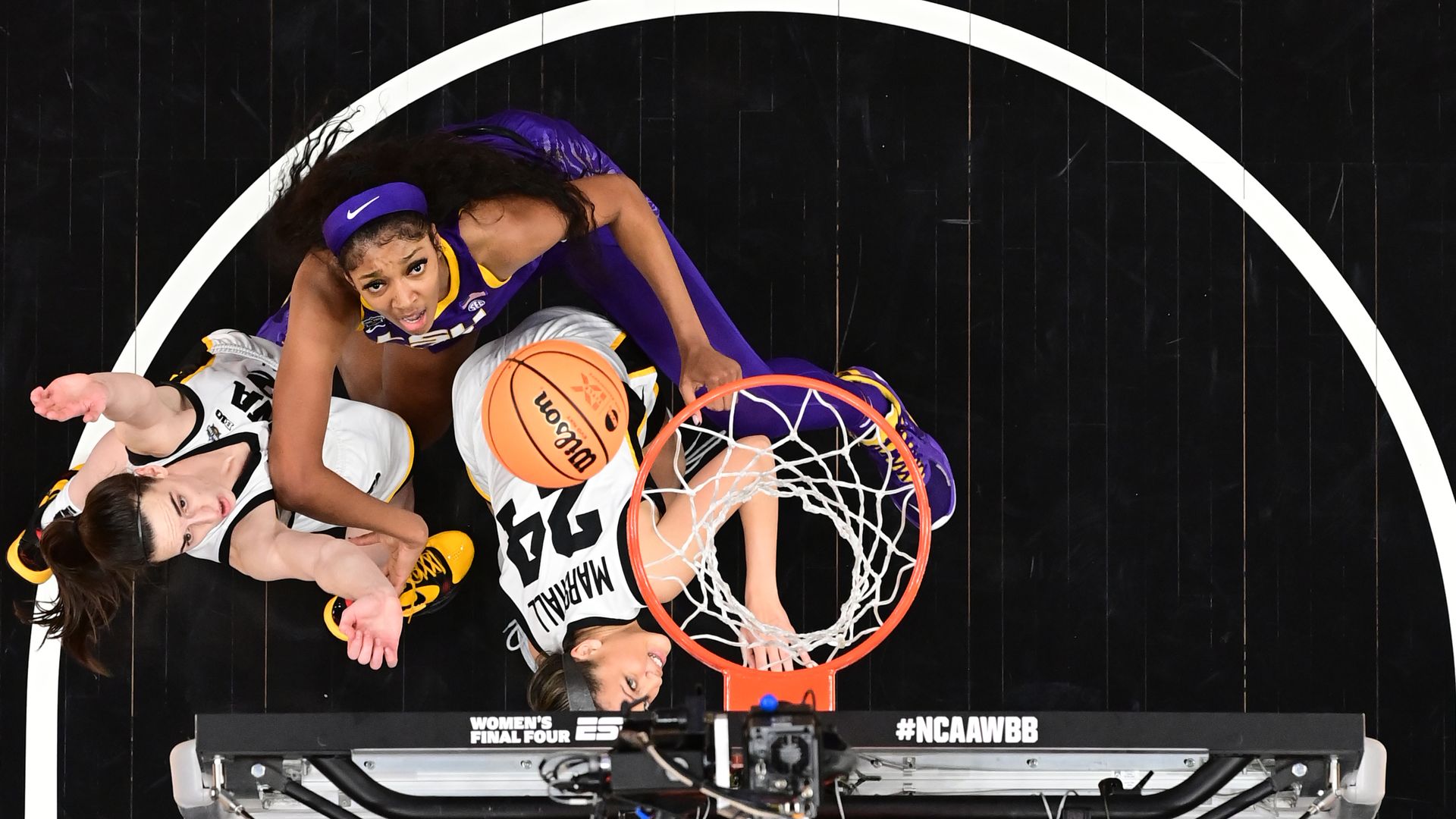 Three basketball players under a hoop