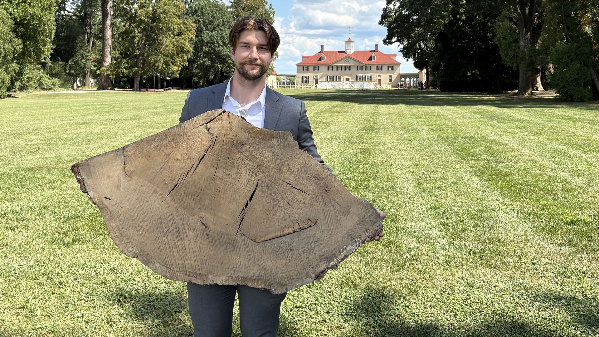 Ryan Jones holding a trunk slice from a tree that once stood in front of George Washington’s home in Mount Vernon. 