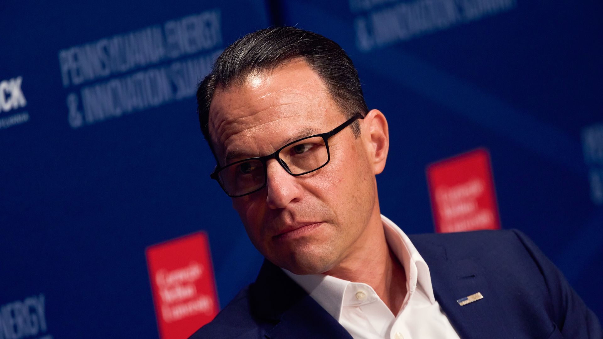 Josh Shapiro looks to the side while on stage at an event.