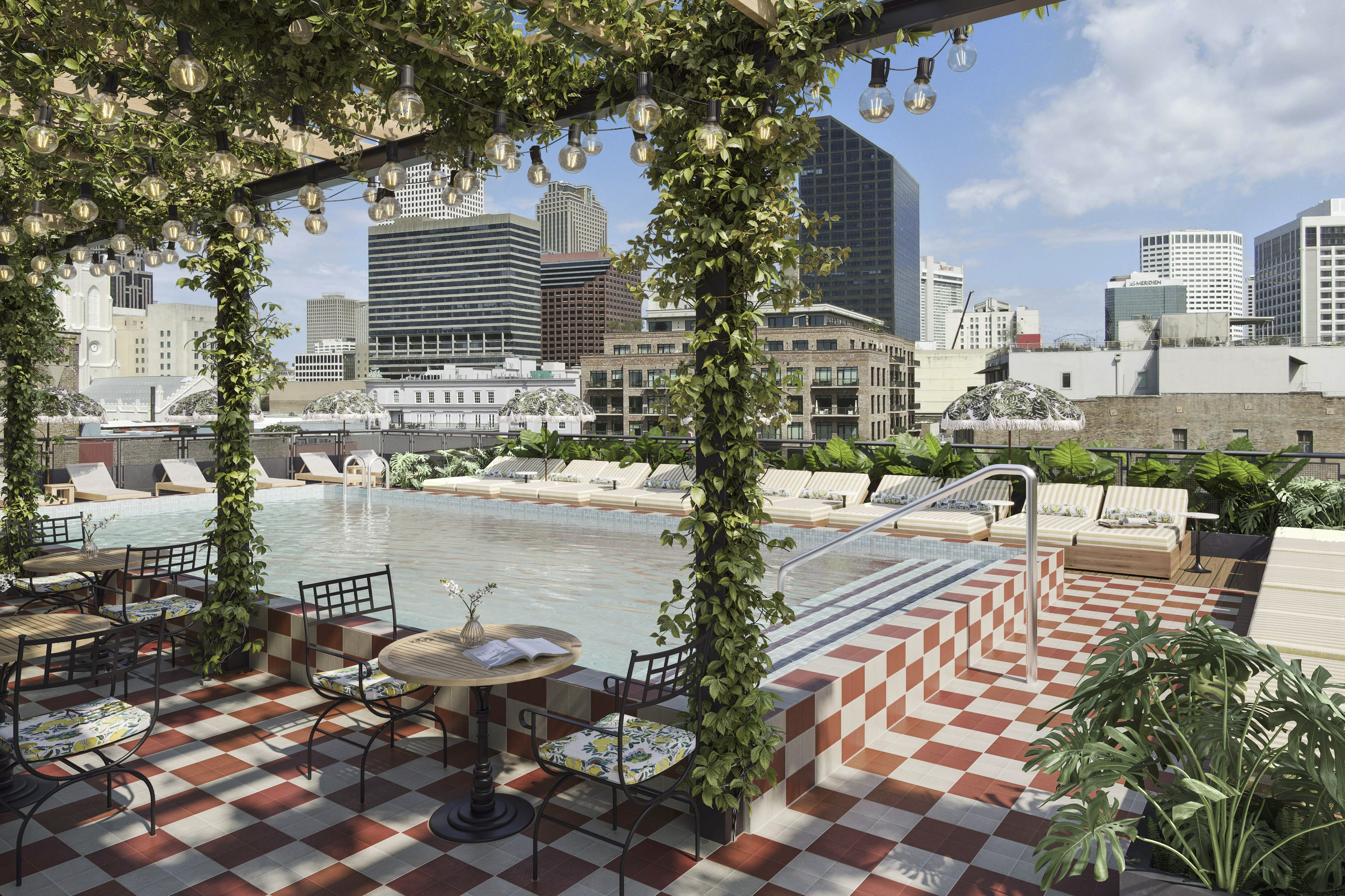 A rooftop pool is surrounded by orange and white checkered tile, lounge chairs and an ivy-covered patio.