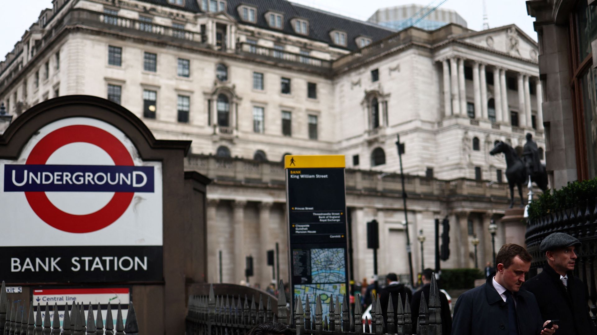 A man gets out of the Bank tube station in front of the Bank of England building