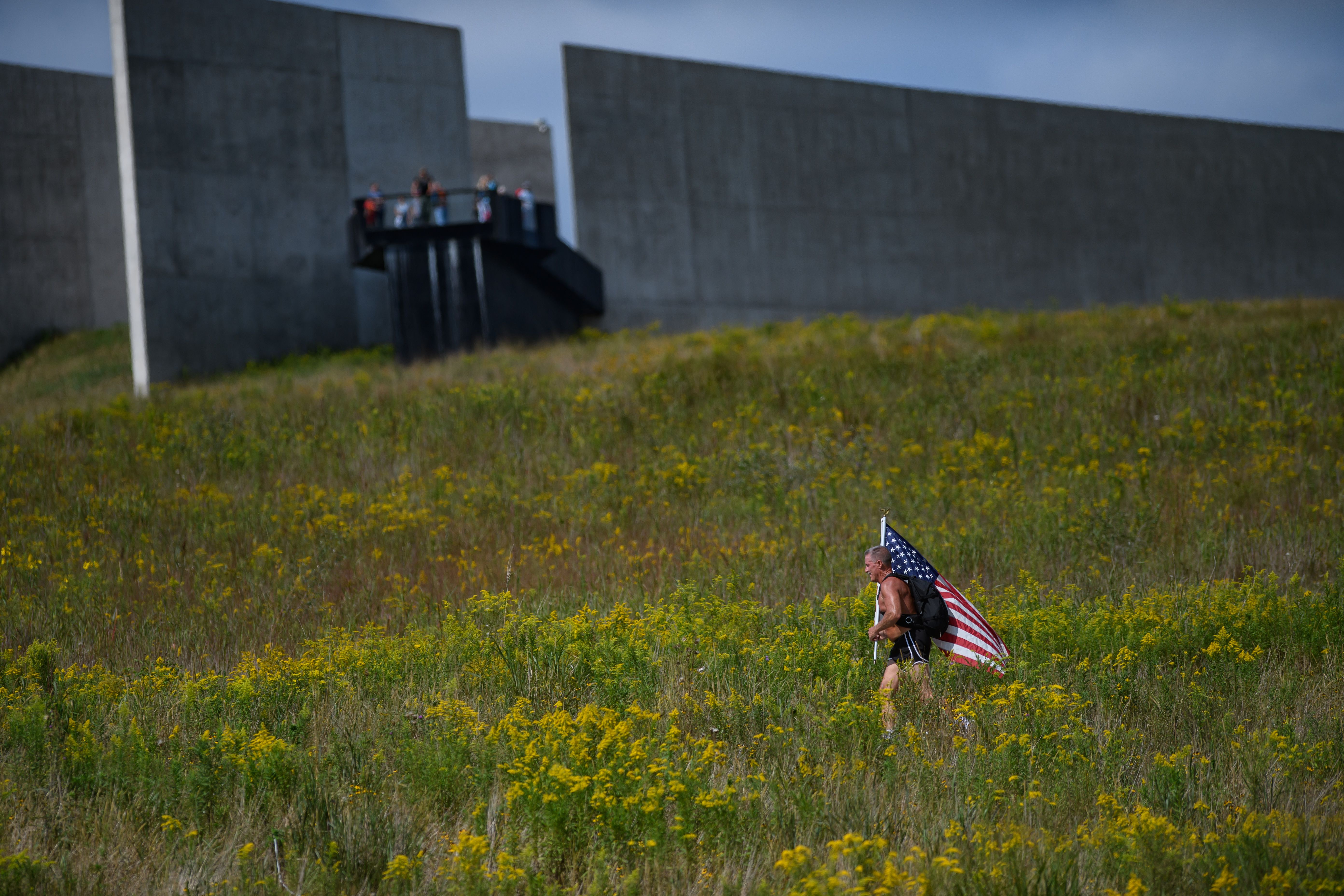 A person running through goldenrod with an American flag at the Flight 93 National Memorial commemoration.