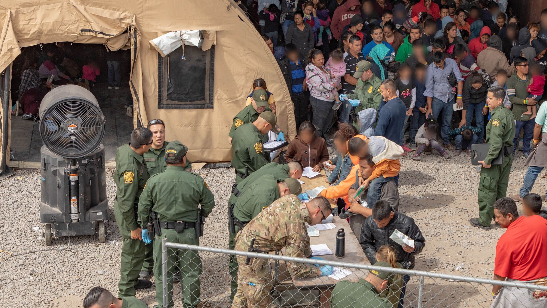 A large group of migrants checking in with CBP officers.