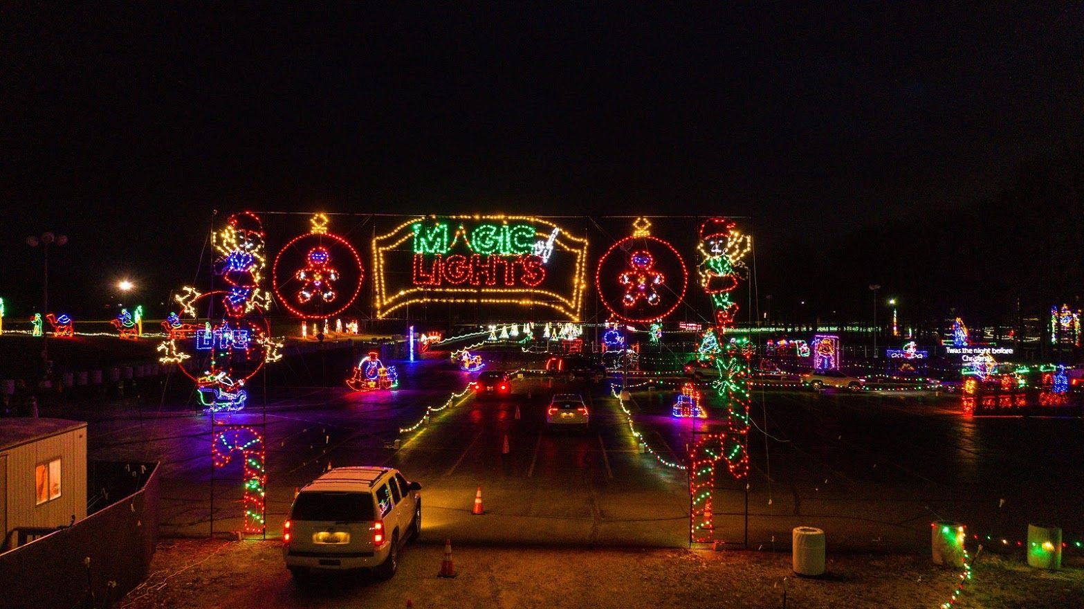 A car drives through a green and red holiday lights display in the dark. 