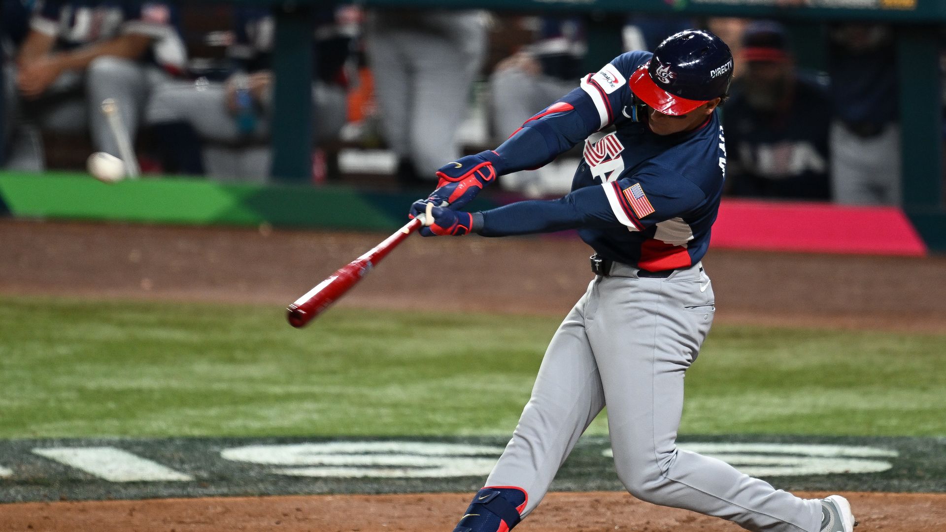 Baseball player Roman Anthony swings a bat while wearing a blue Team USA uniform with gray pants. The hit was a home run.