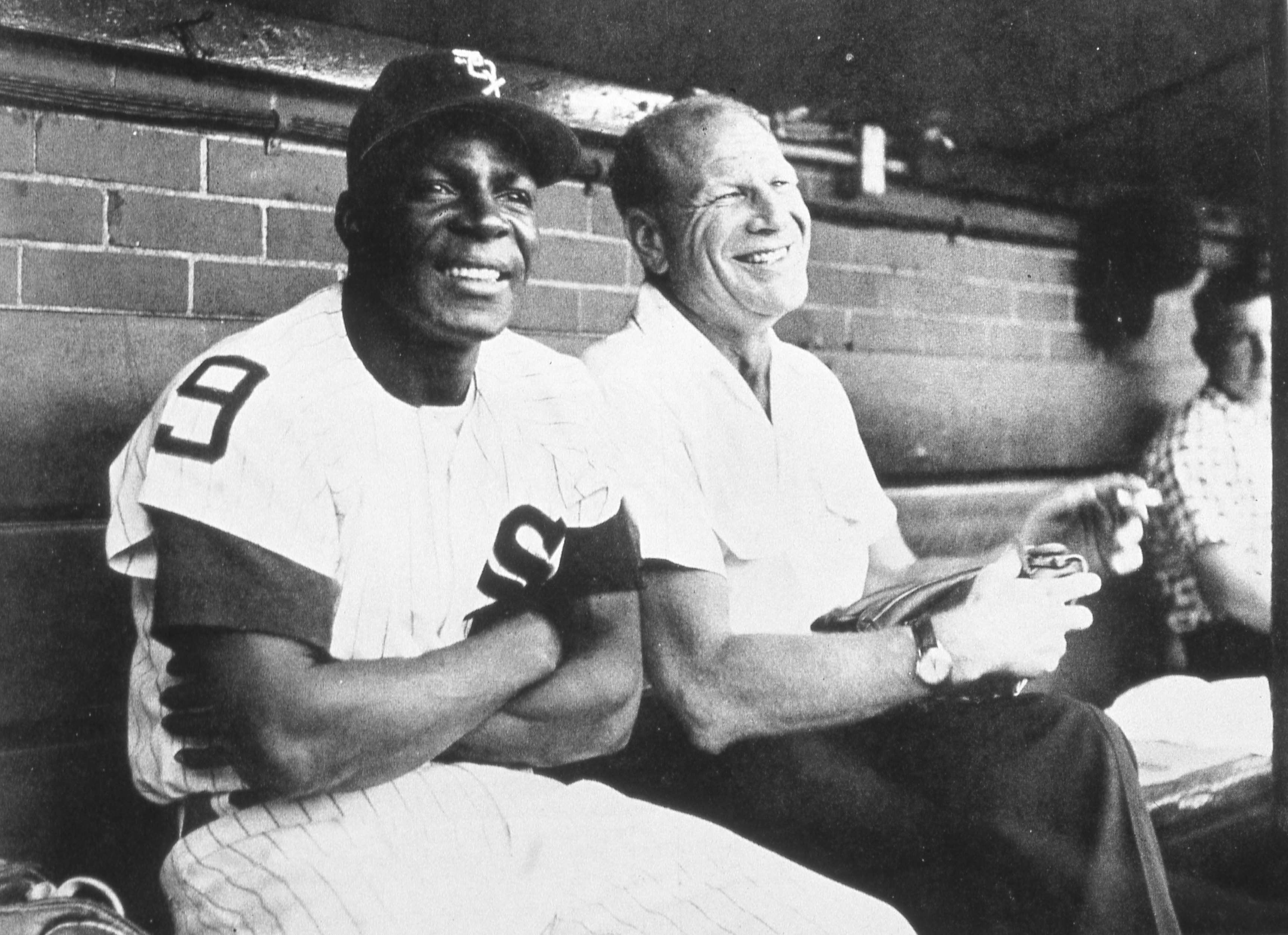 Photo of a man in a baseball uniform sitting down smiling 