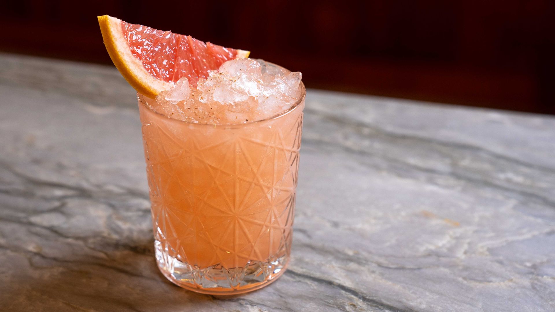 A bright orange mocktail with a piece of grapefruit