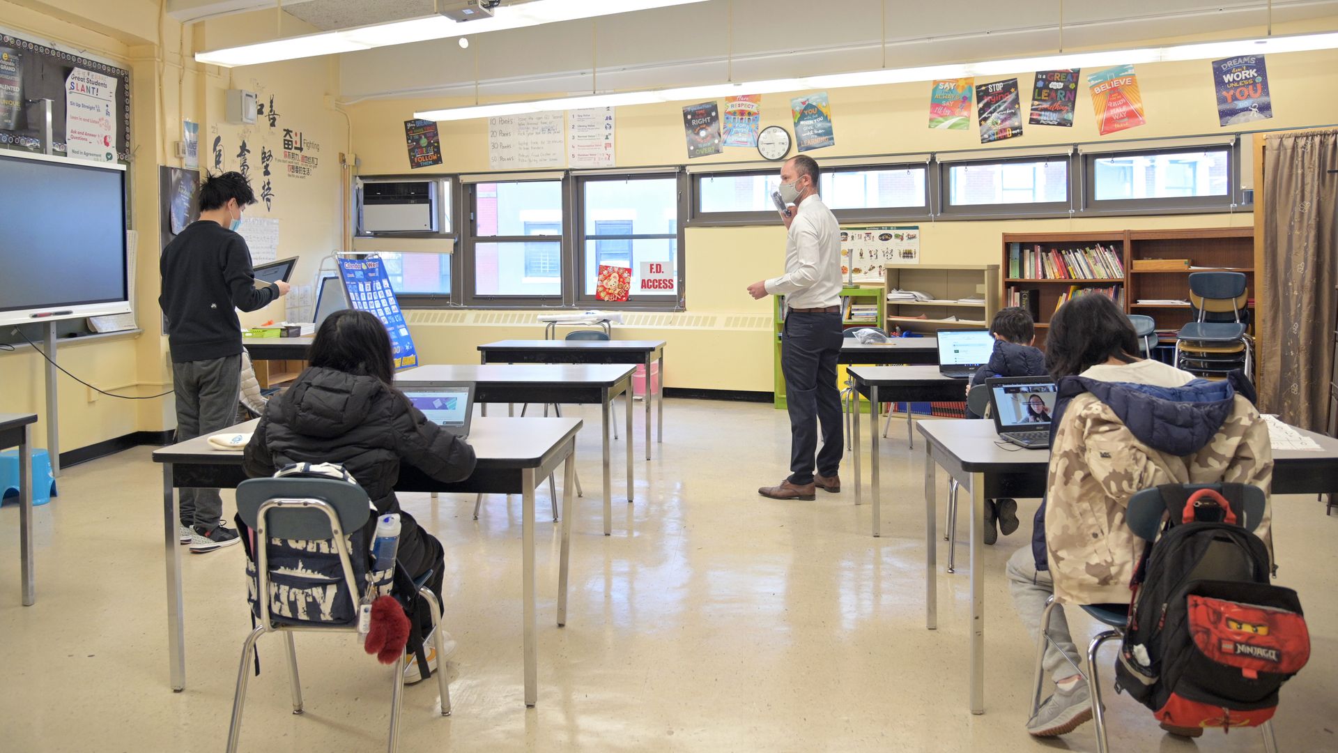 Principal Ben Geballe (C) helps students settle into a classroom at Sun Yat Sen M.S. 131 on February 25, 2021 in New York City.