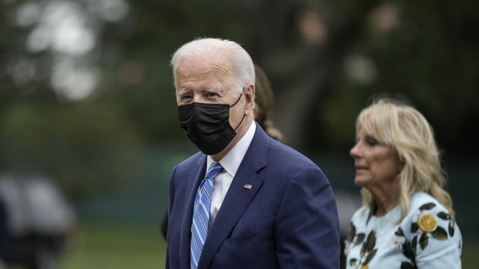 Photo of Joe Biden wearing a mask walking on the White House lawn with Jill Biden