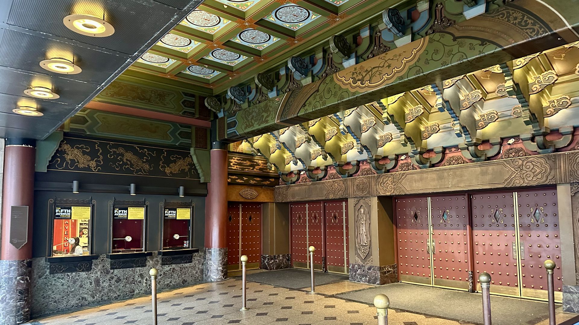 A look at the decorative entrance to the 5th Avenue Theatre with wooden paneling on the ceiling and box office windows at left.