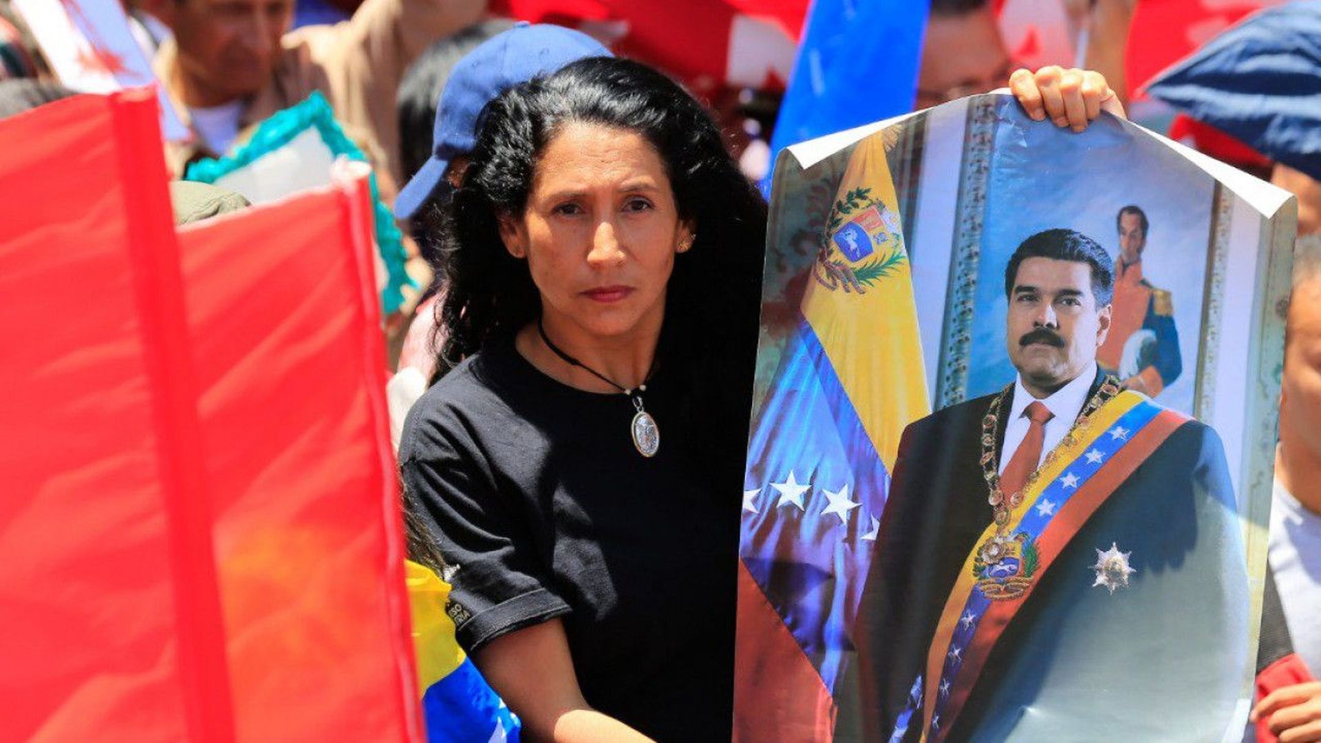 In this image, a woman holds a poster of Maduro outside during a protest.