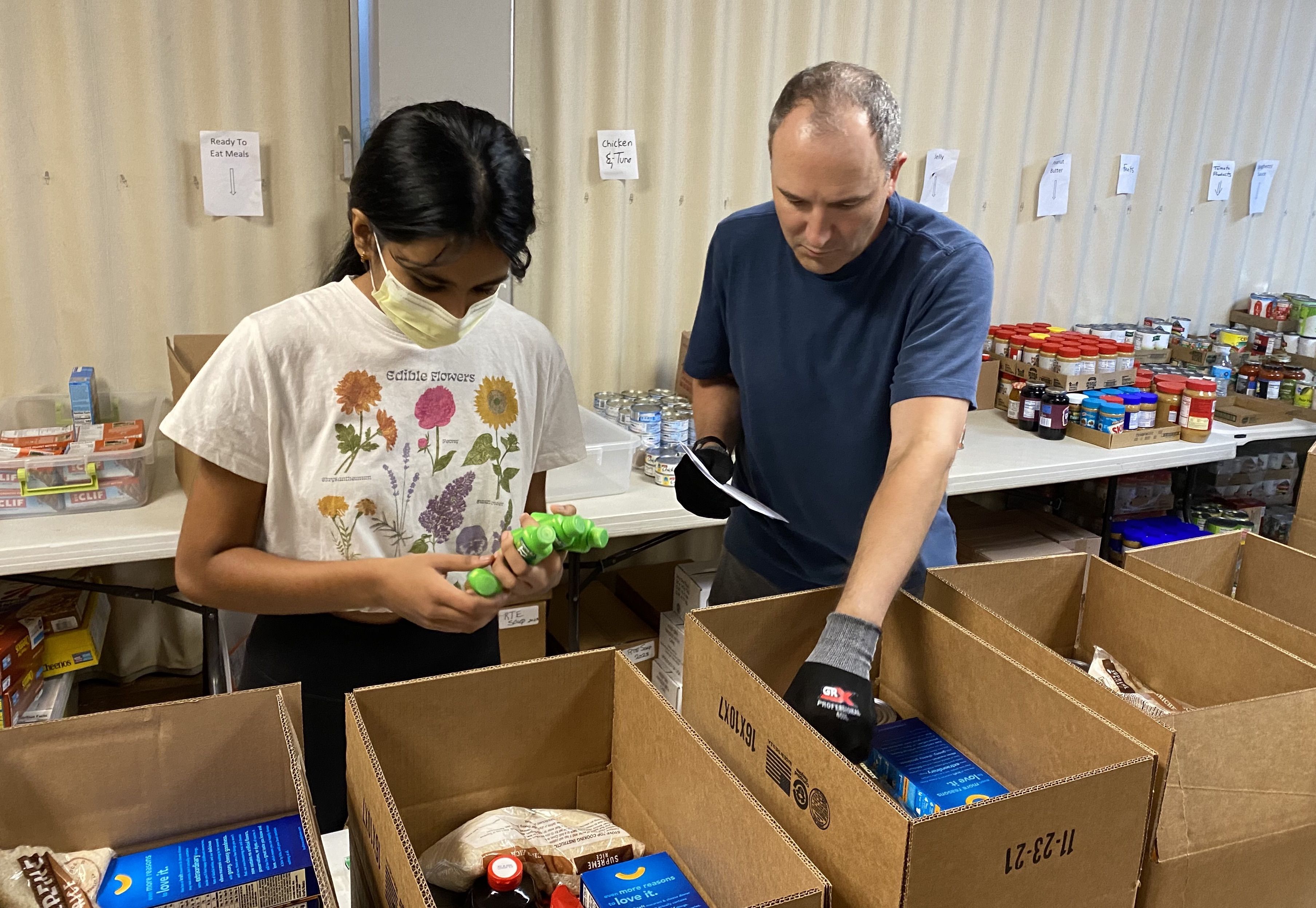 Two volunteers fill boxes with nonperishable food