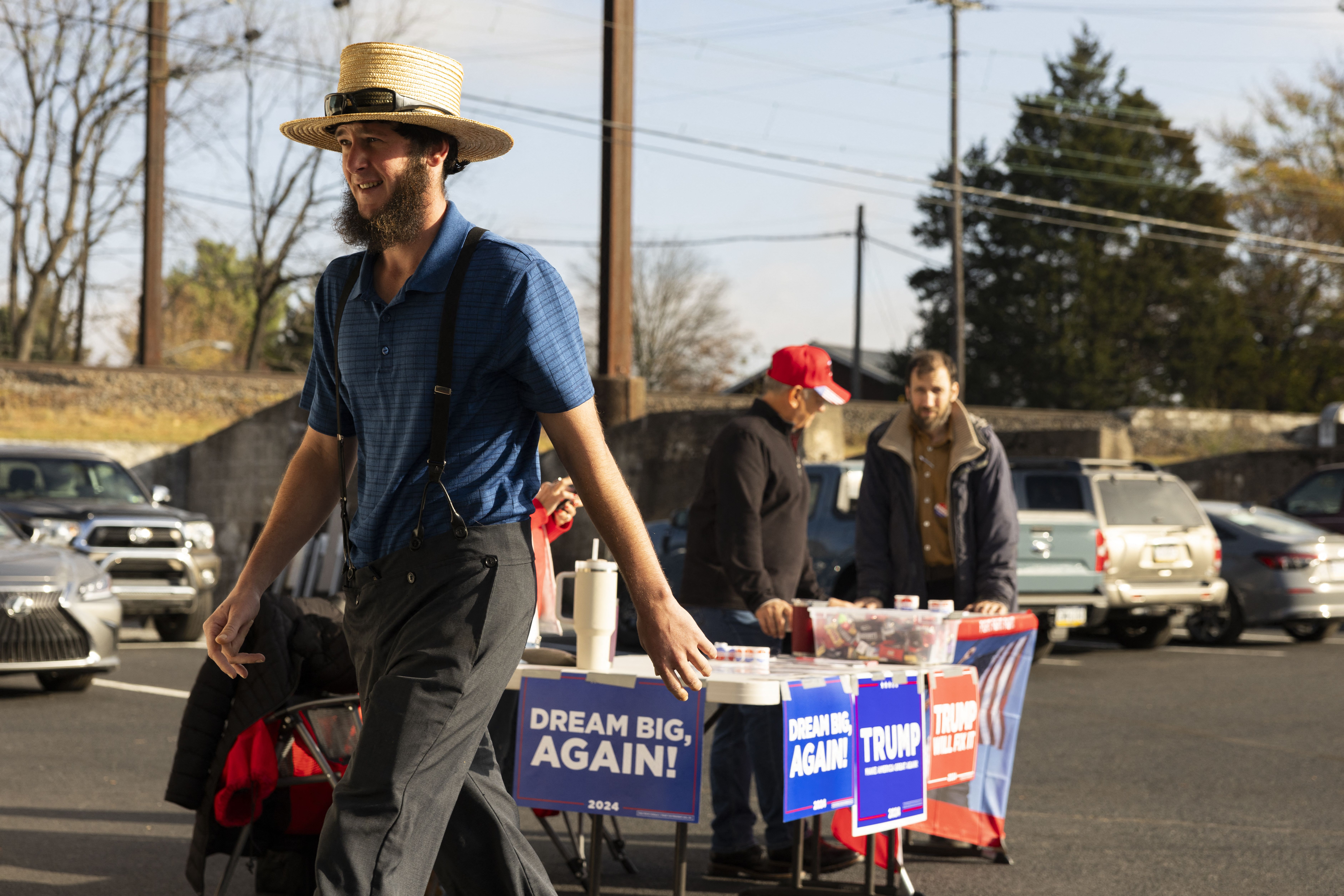 An Amish man walks past a Donald Trump campaign table outside a polling location. 