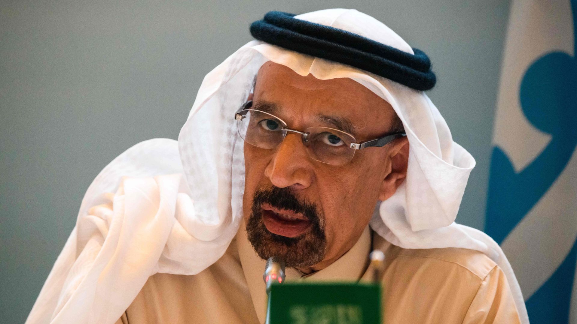 This image is a close-up of Saudi Energy Minister Khalid Al Falih talking. A blurred miniature Saudi Arabian flag sits in front of him.