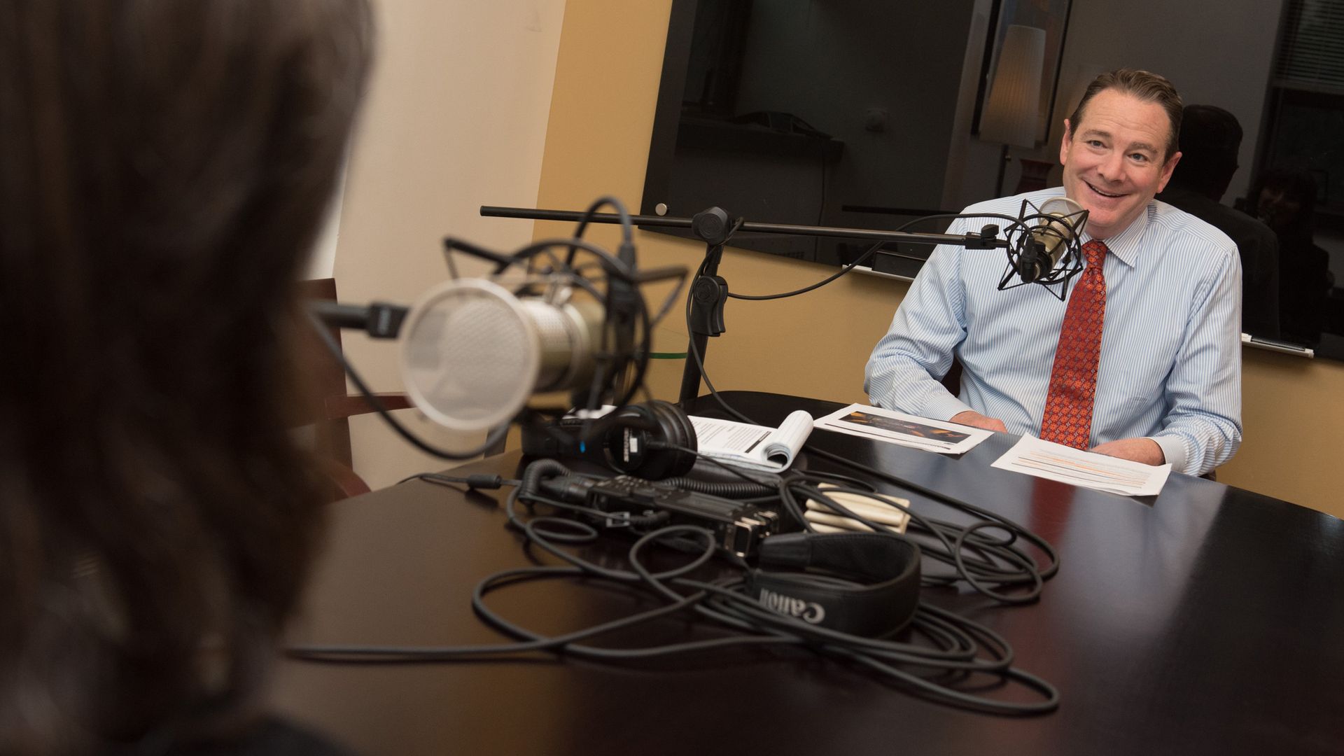 Photo of a man sitting behind a microphone.