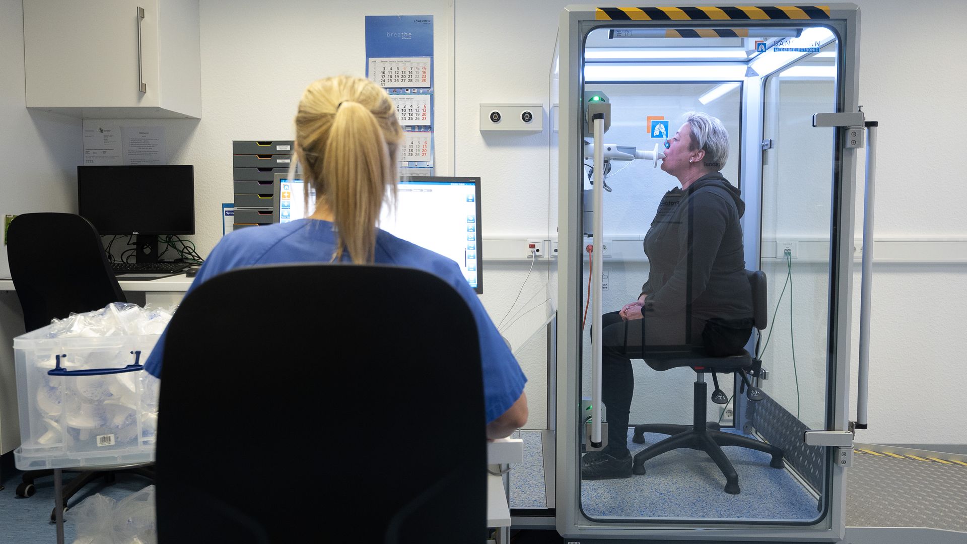 Picture of a patient in a glass box taking a respiratory test