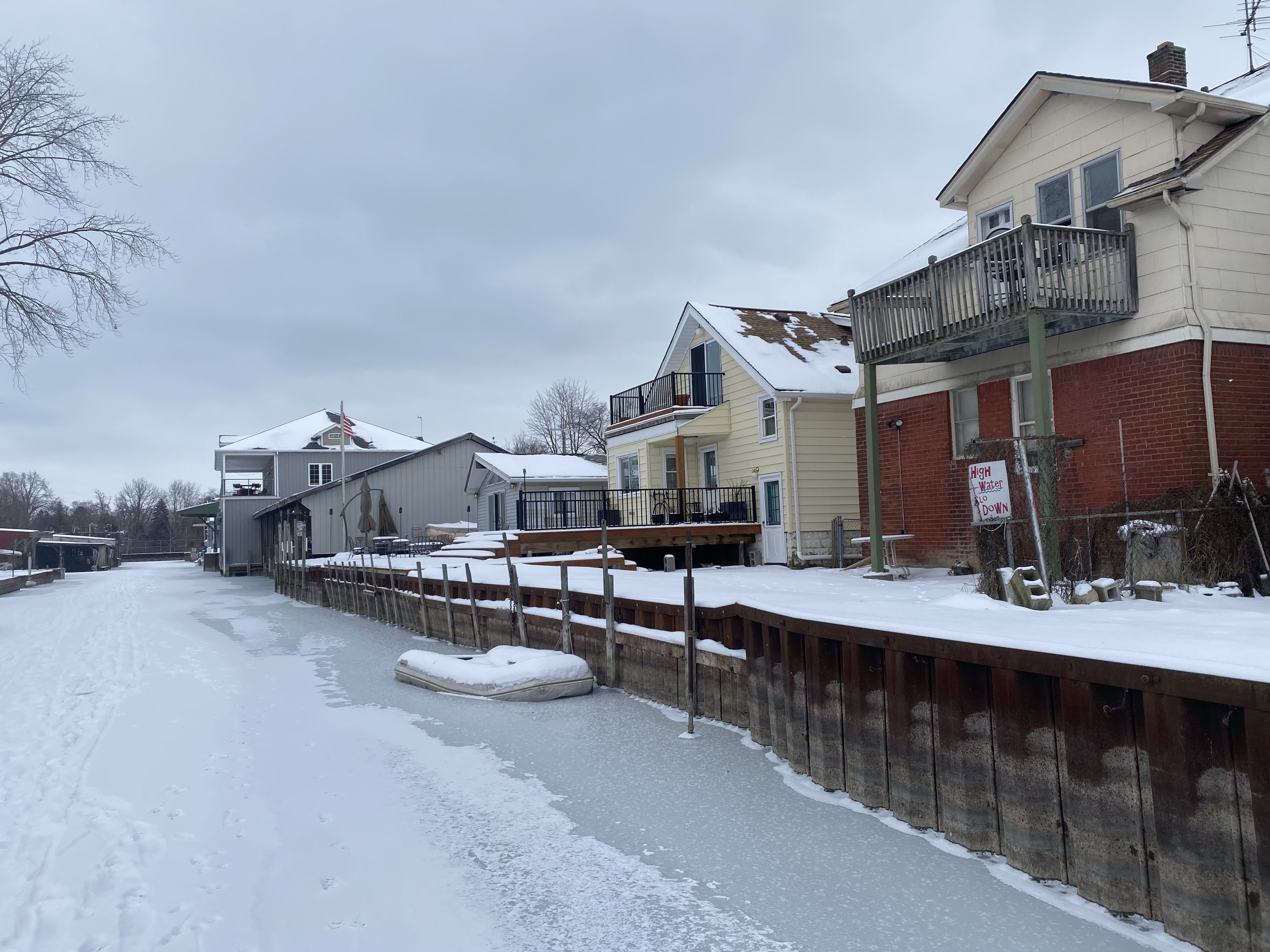 The canals, frozen over, allow someone who walks through a unique perspective. The houses along the canal are seen from the back, with ice covering the canal itself.