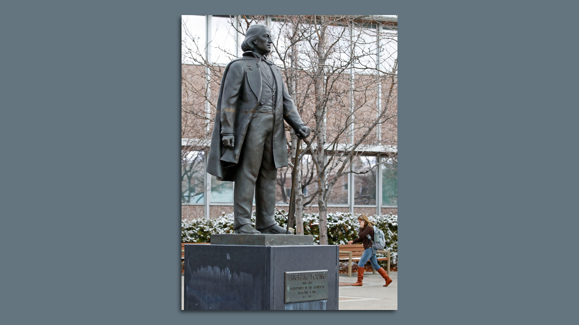 A person walks past a statue of Brigham Young at BYU.