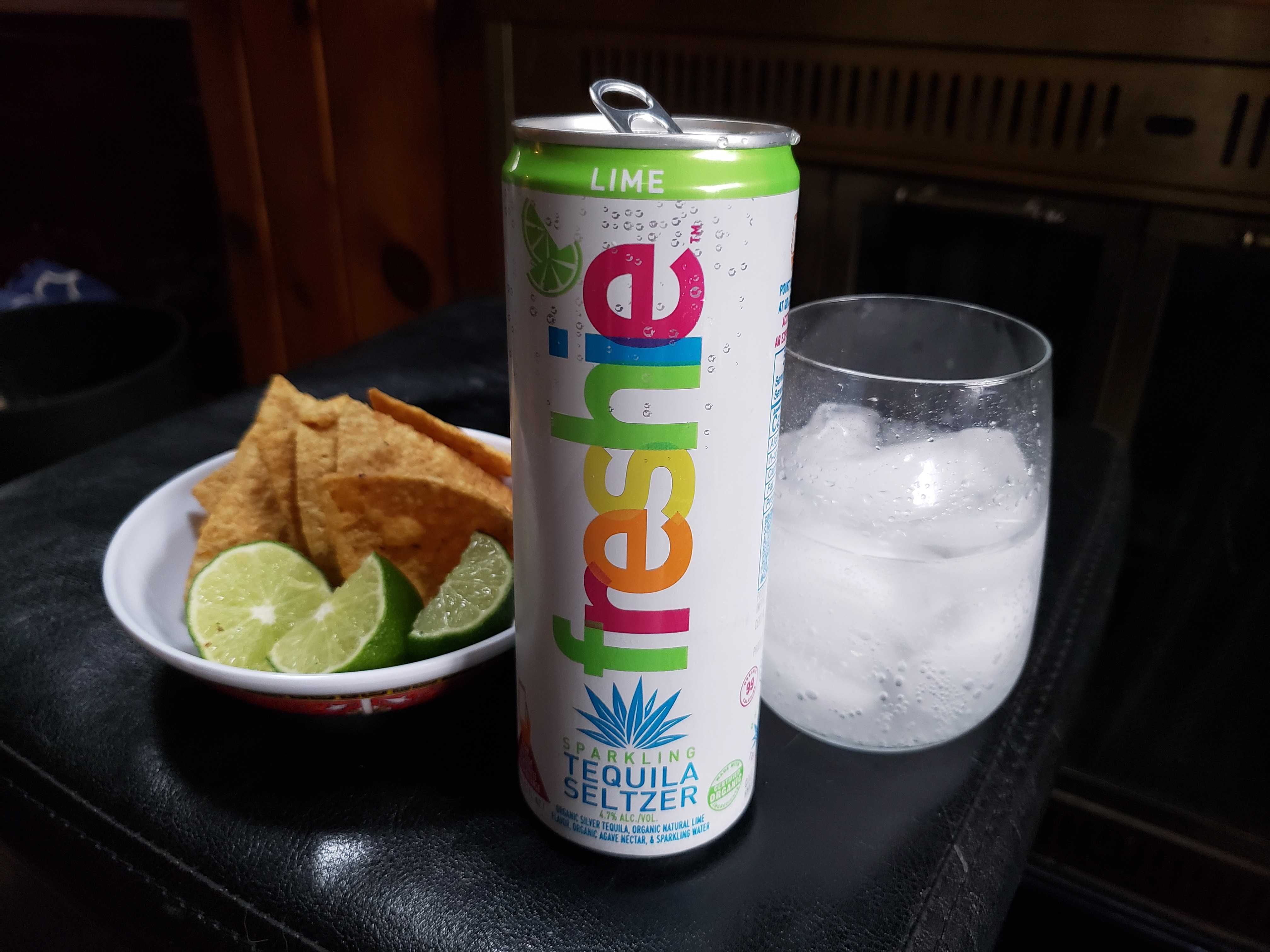 Photo of a can of tequila water next to a plate of tortilla chips. 