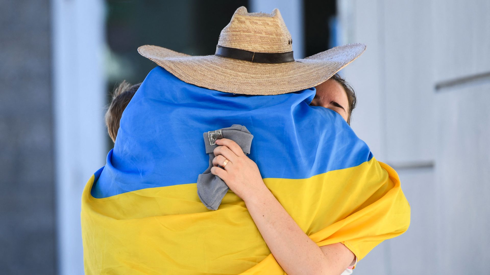 Oleksii Yeromin, wrapped in a Ukrainian flag, hugs a Ukrainien refugee as they cross the San Ysidro PedWest port of entry along the US-Mexico border between Tijuana, Baja California, and the U.S.