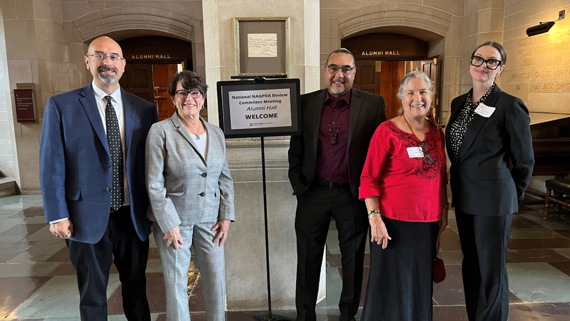 Five people stand outside a meeting room.