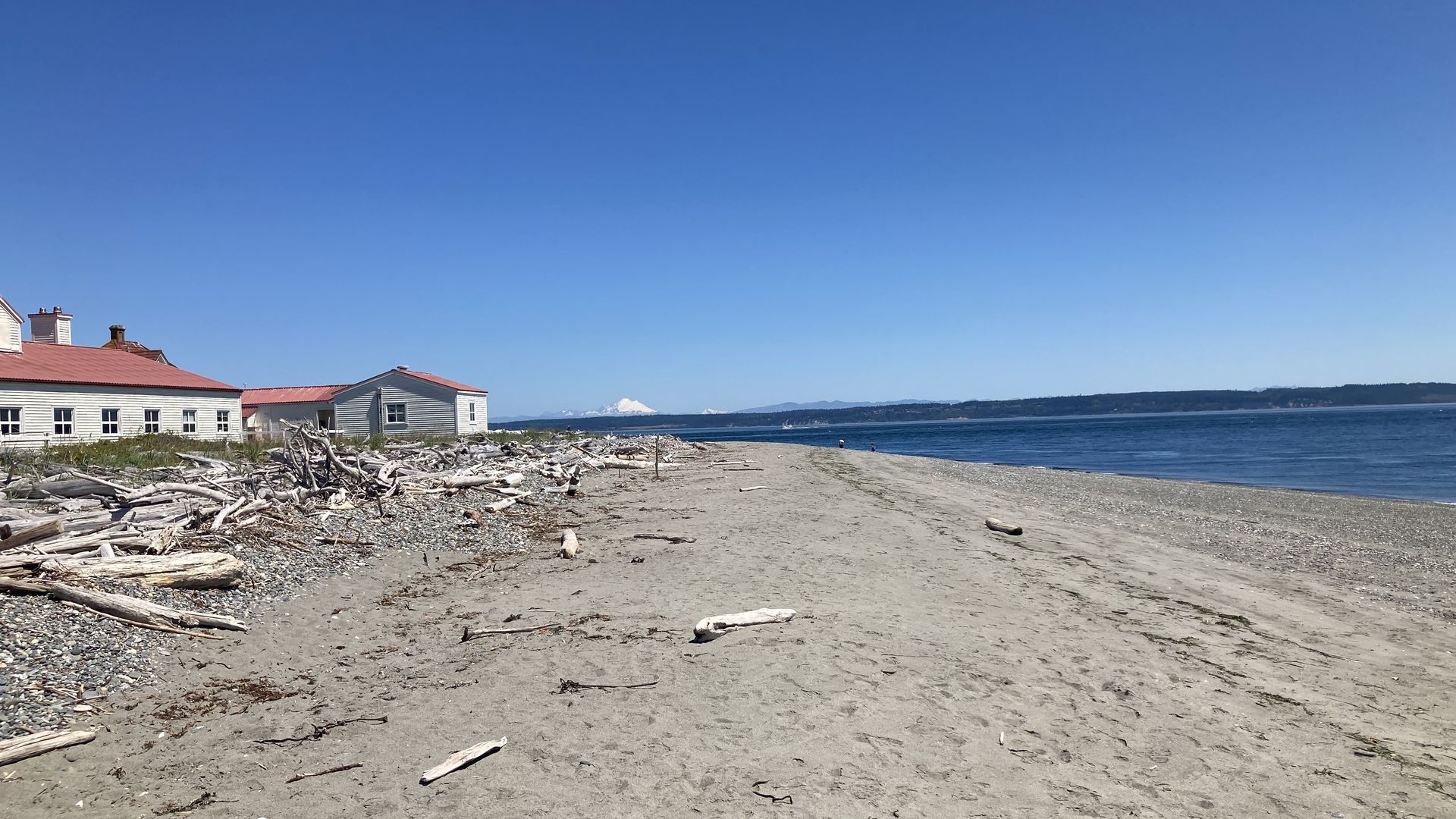 A view of a beach with a military building along the shore and a mountain in the distance.