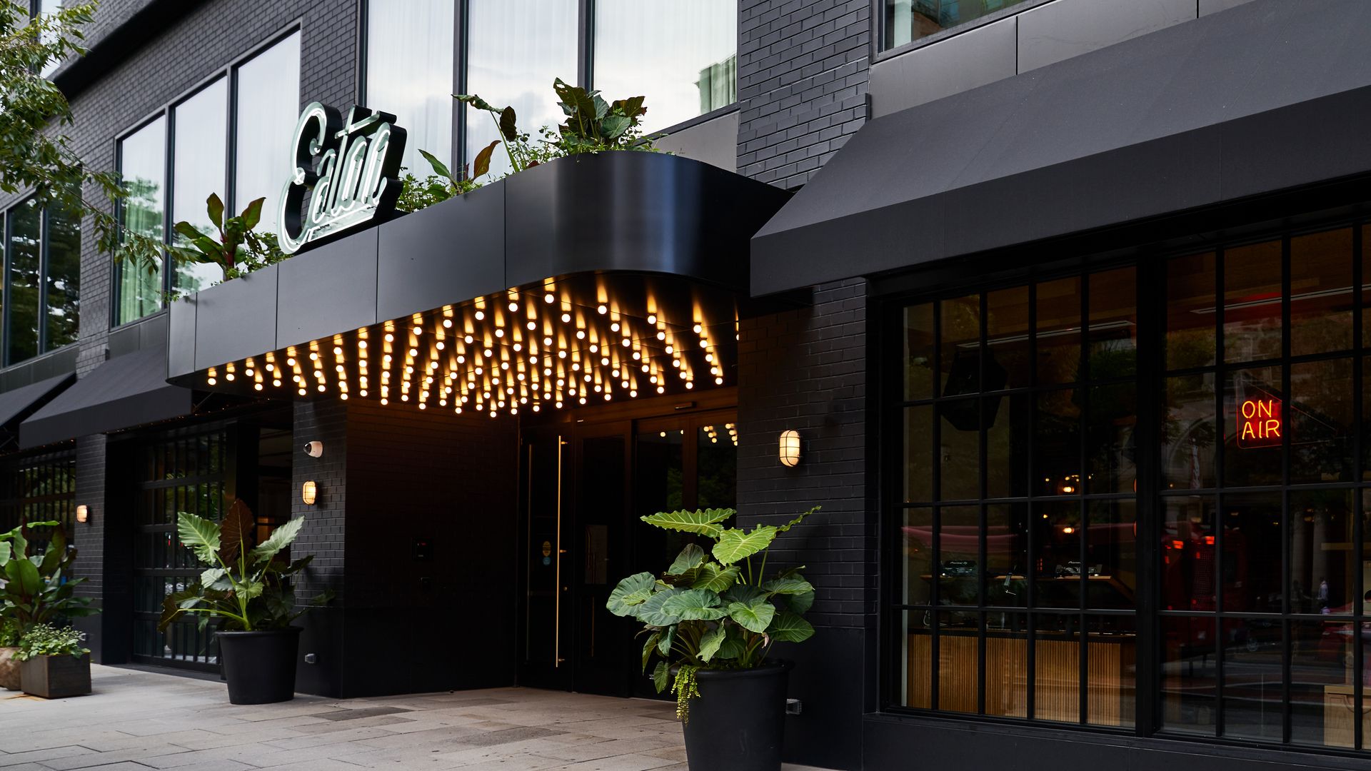 A black brick building with a large sign that reads "Eaton" and bright lighting below. 