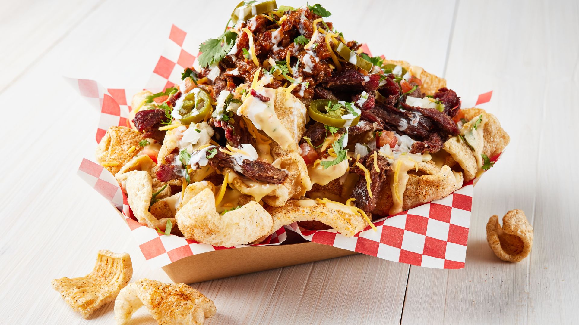 A pile of meat and cheese and peppers on chicharron