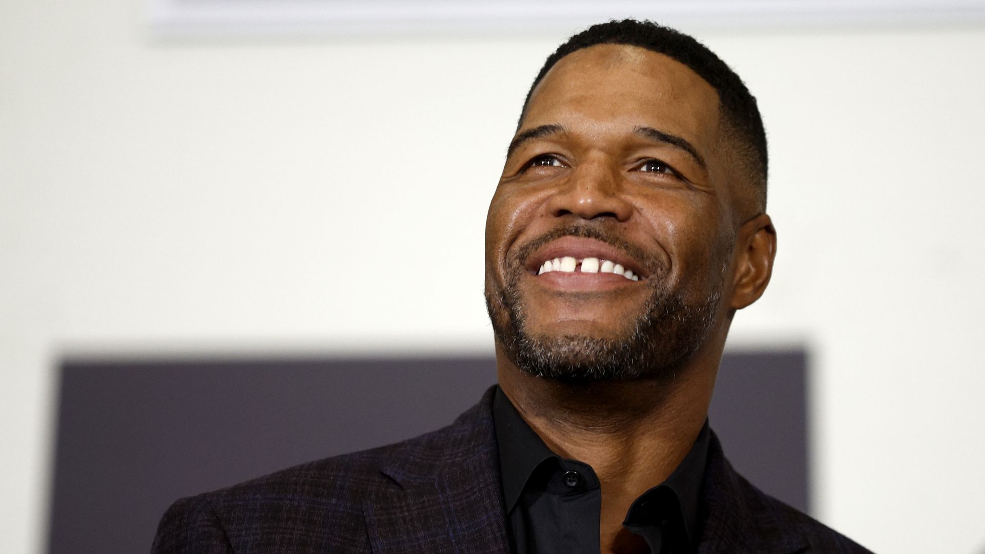 A man smiles in a shirt with a collar clinging to his neck 