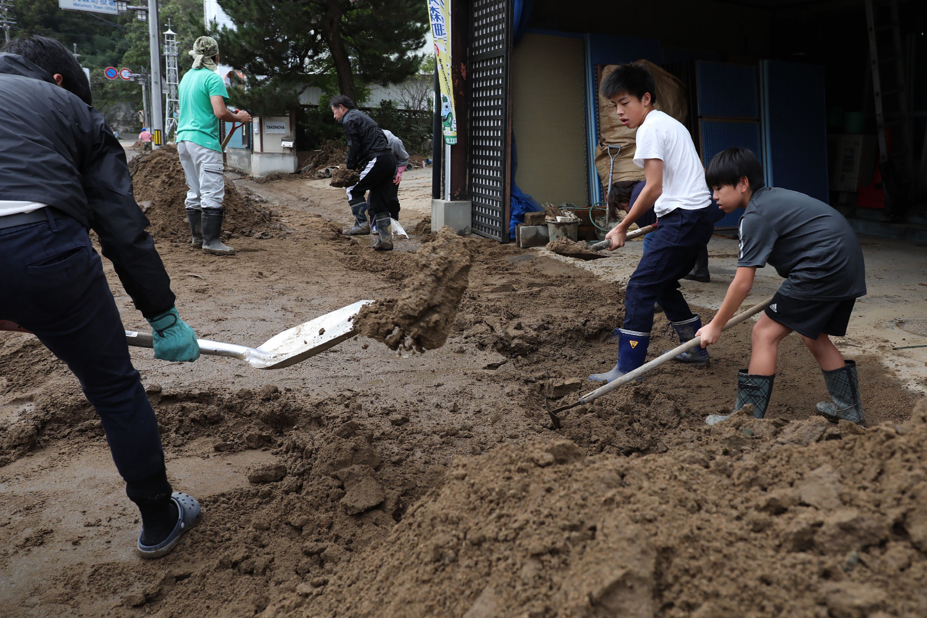 Residents clear mud from a street at the flooded area in Marumori, Miyagi prefecture 